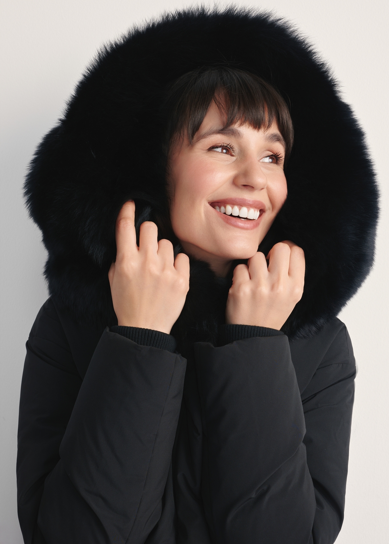 Czarna kurtka damska z futrem naturalnym lisa KURDT-0594-99(Z25) - zbliżenie na detal z przodu na modelce na białym tle. 