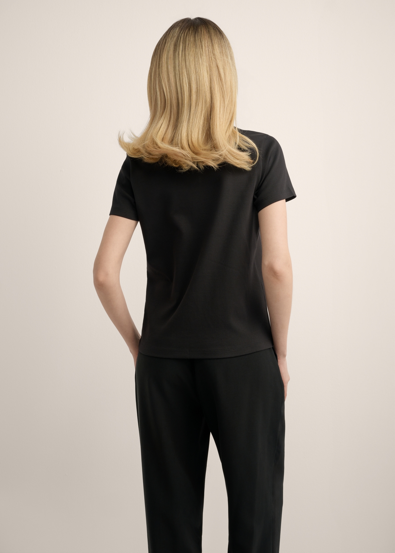 Czarny bawełniany t-shirt damski TSHDT-0144-99(Z25), widok produktu z tyłu na modelce. Widoczna połowa sylwetki.