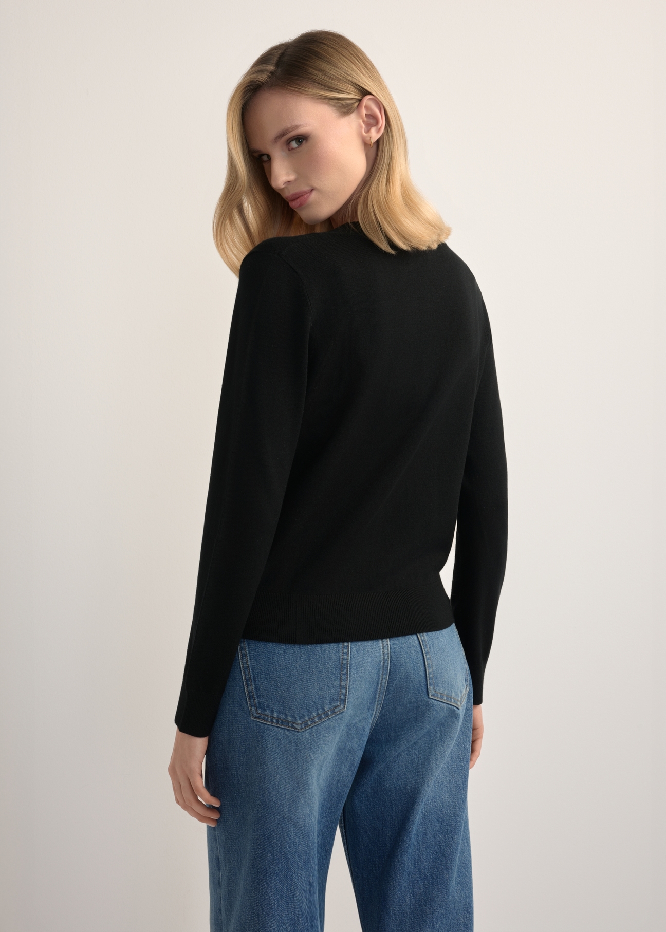 Czarny kardigan damski KARDT-0061-99(W26), widok produktu z tyłu na modelce. Widoczna połowa sylwetki.