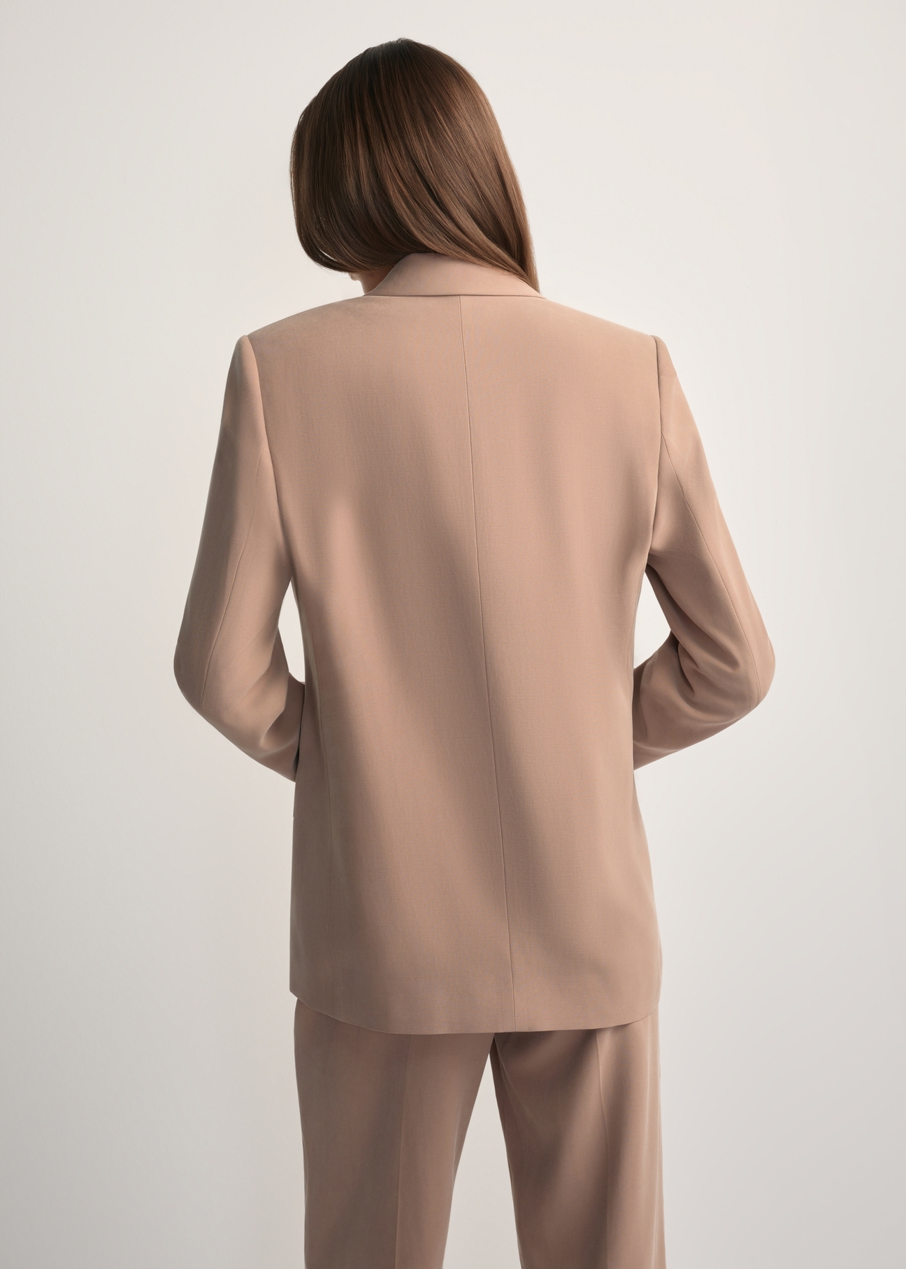 Marynarka damska w kolorze camelowym ZAKDT-0031A-1D(W26) - widok produktu z tyłu, na modelce, na jasnym tle. Widoczna połowa sylwetki.