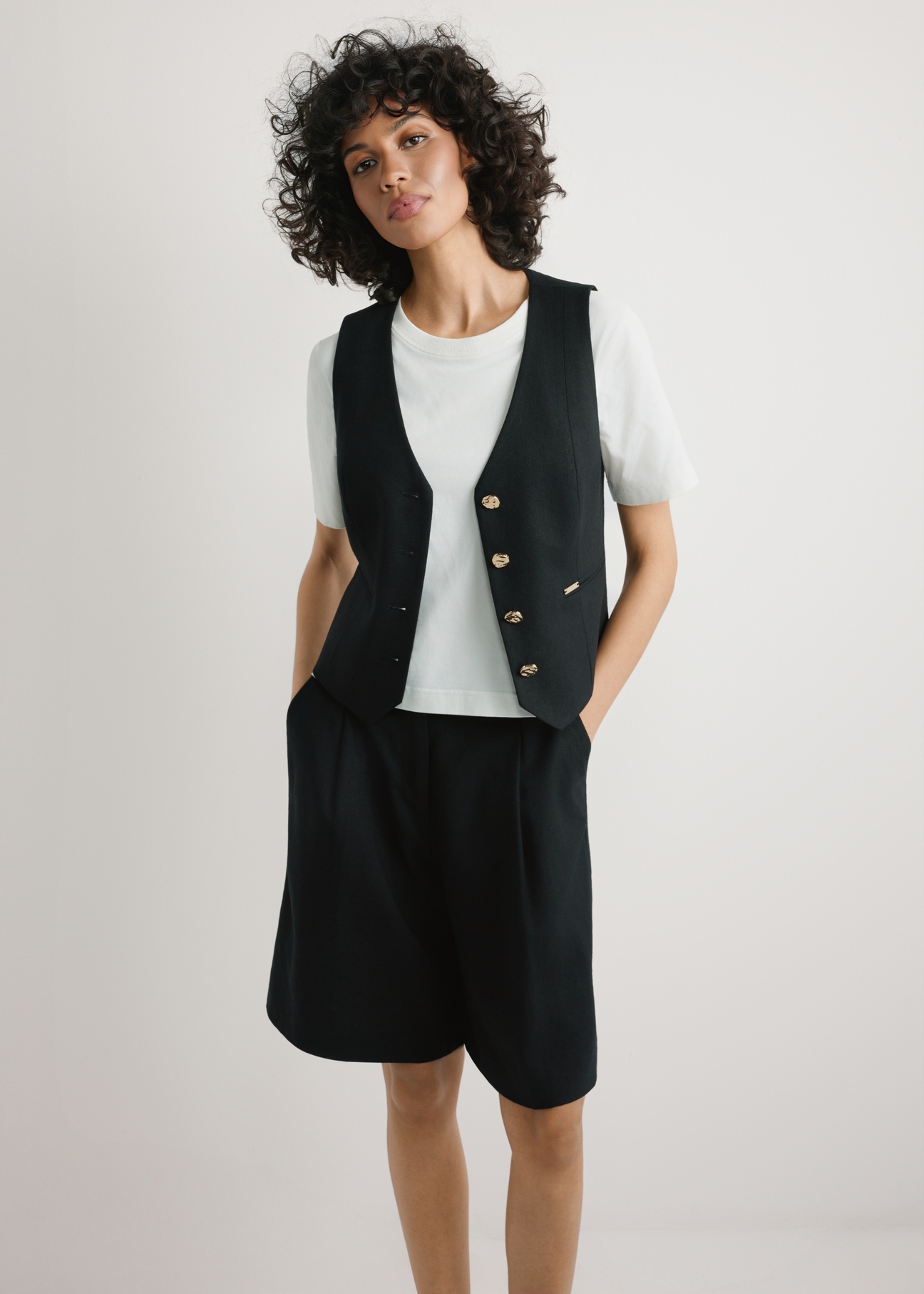 Czarna kamizelka z wiskozy i lnu KAMDT-0038-99(W26) - widok produktu z przodu, na modelce, na jasnym tle, Widoczna sylwetka do kolan. 