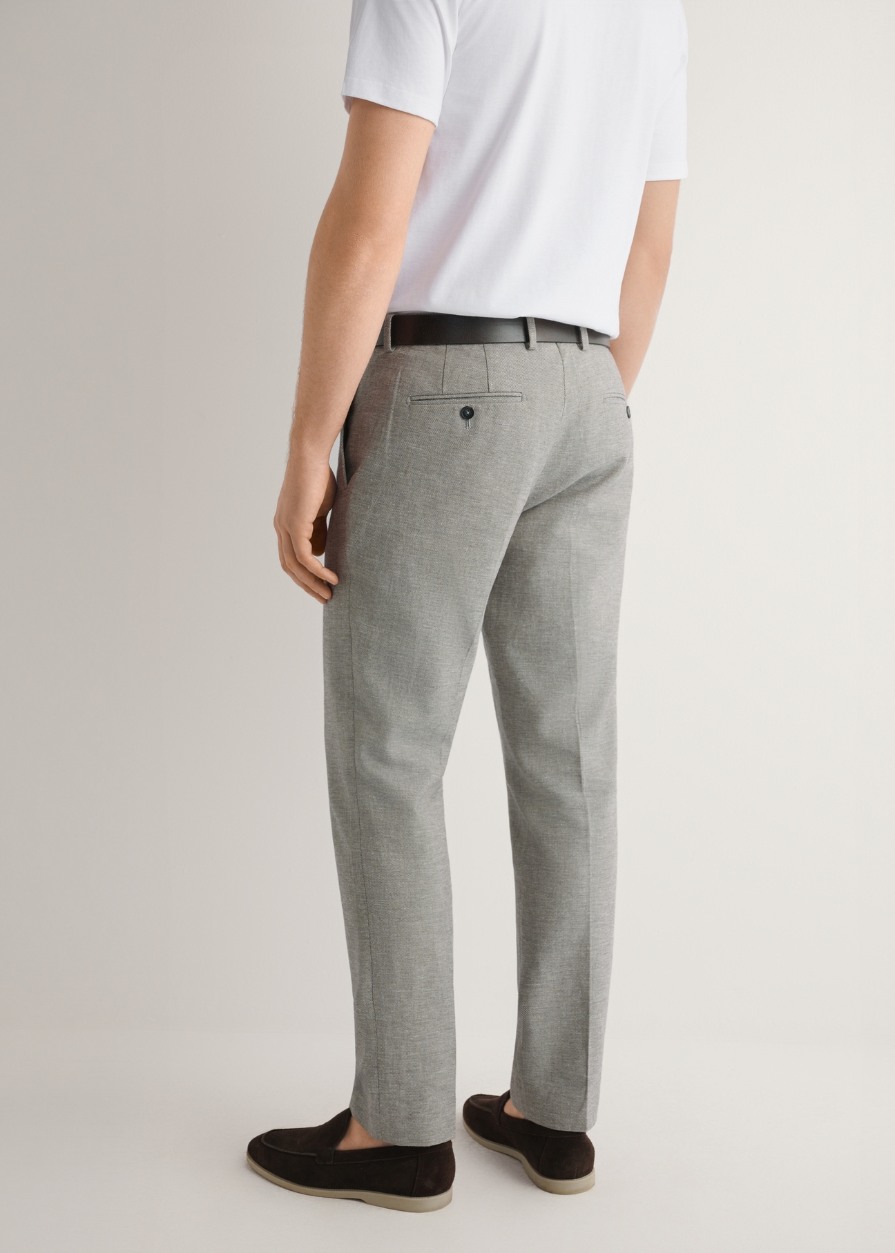 Beżowe spodnie garniturowe męskie SPOMT-0098-1B(W26), widok produktu z tyłu na modelu. Widoczna połowa sylwetki.