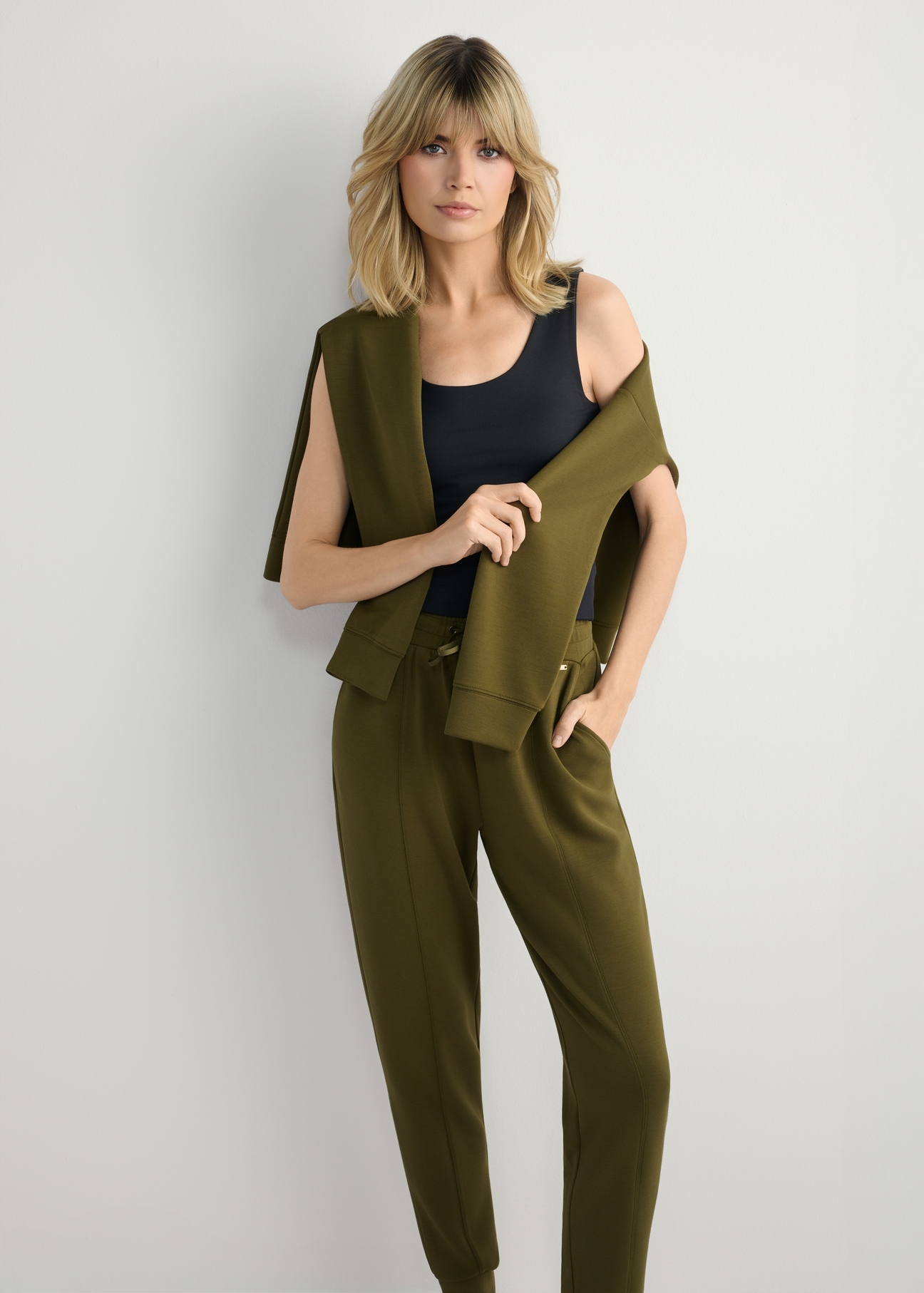 Bluza damska khaki z kapturem BLZDT-0111A-8D(W26), widok produktu na ramionach modelki. Widoczna cała sylwetka.