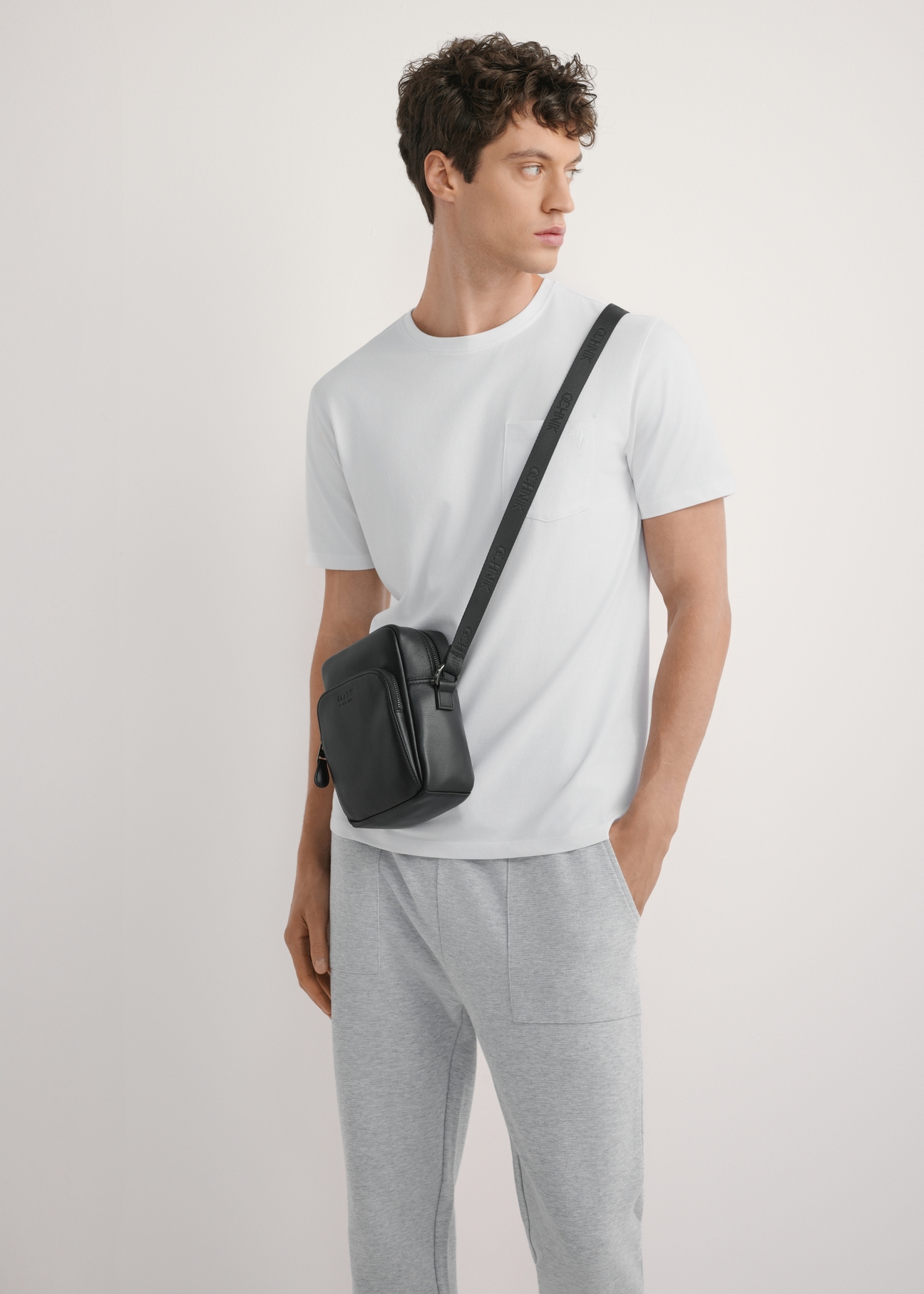 Czarna skórzana saszetka męska TORMS-0485R-9I(W26), widok produktu od przodu na modelu, widoczna połowa sylwetki.