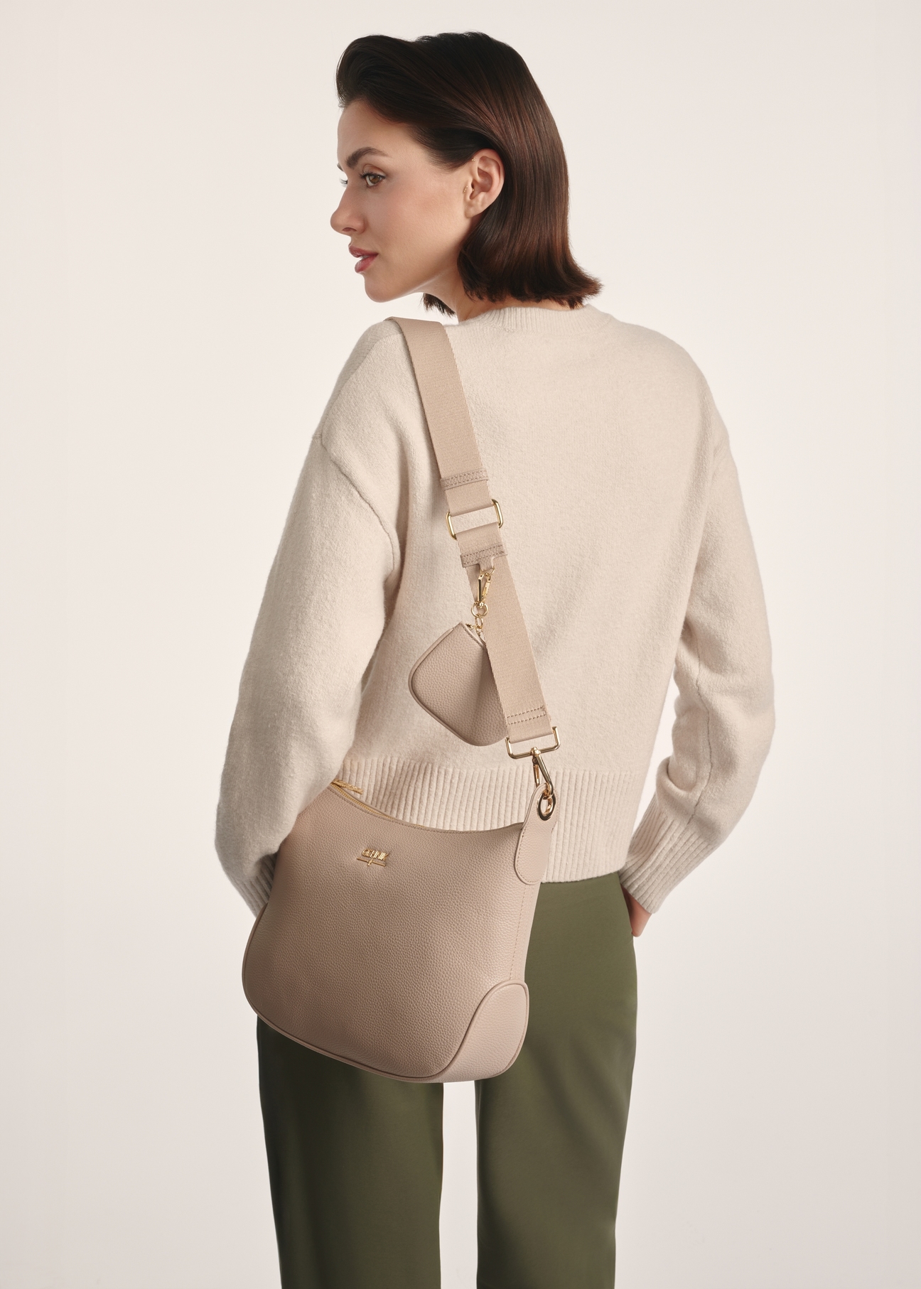 Beżowa torebka damska w stylu hobo TOREC-0829A-80(Z25), widok produktu na ramieniu modelki. Widoczna połowa sylwetki.