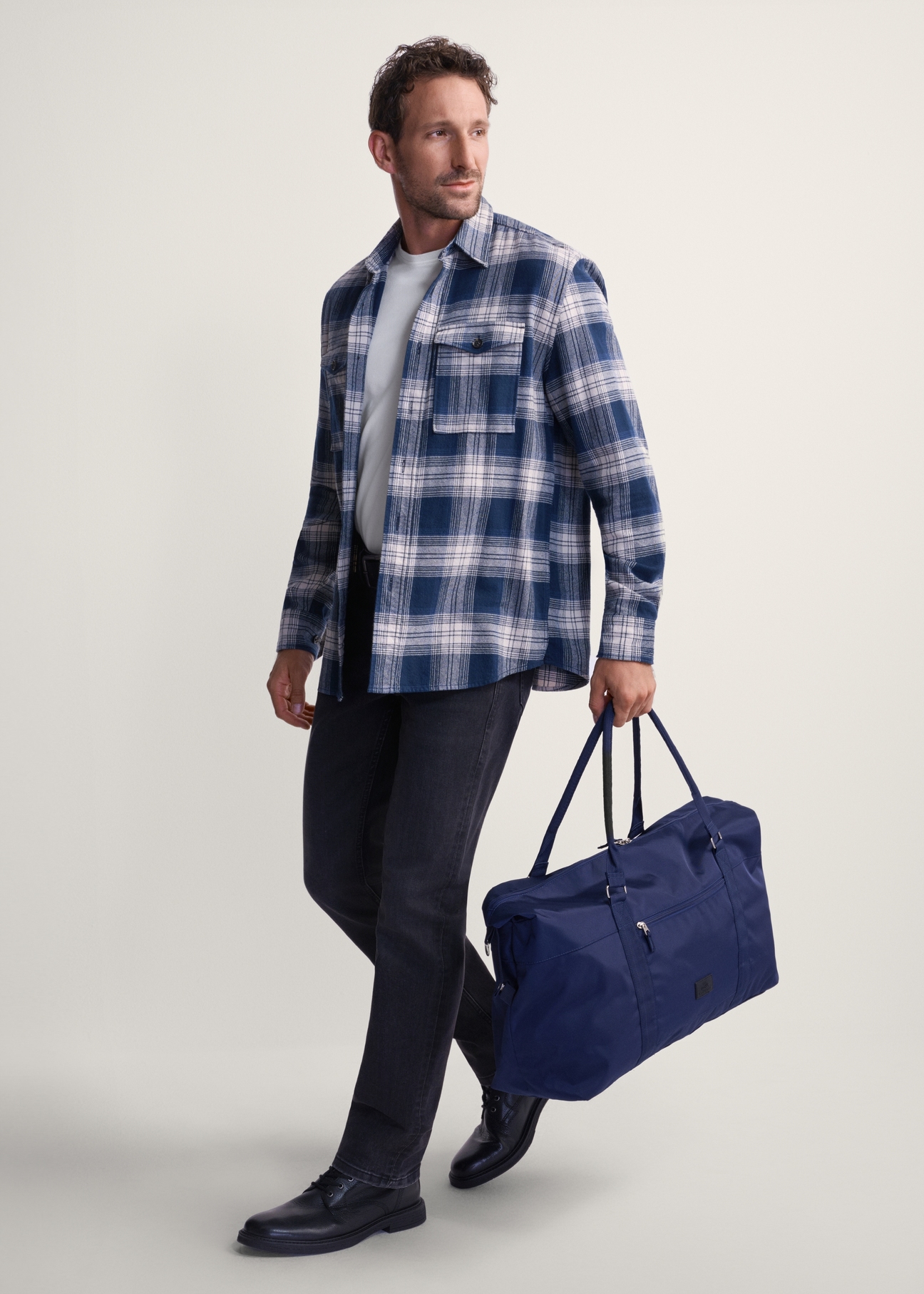 Granatowa torba podróżna TORMN-0382-69(Z25), widok produktu w dłoni modela. Widoczna cała sylwetka.