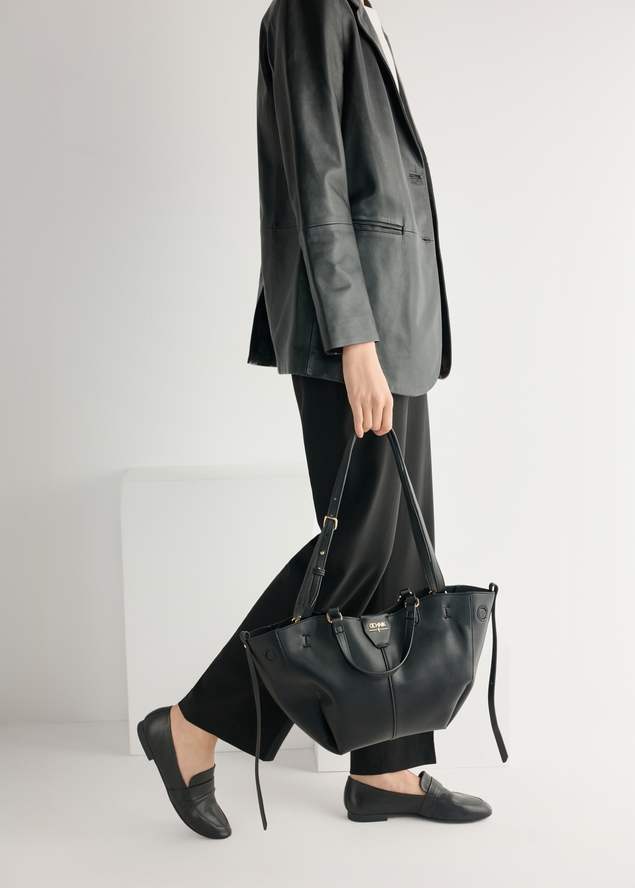 Skórzane czarne mokasyny damskie BUTYD-1074A-99(W26), widok produktu od przodu na modelce, widoczna połowa sylwetki.