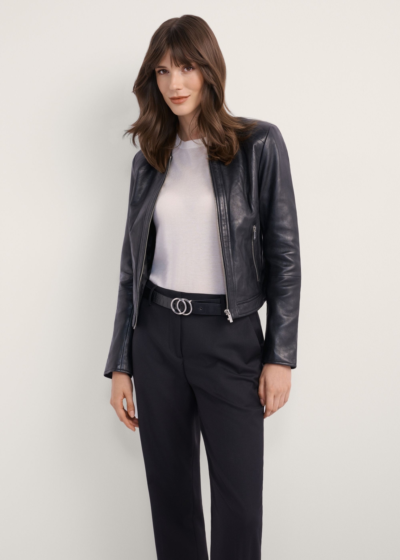 Czarna krótka kurtka skórzana damska KURDS-0294-99(KS), widok produktu z przodu na modelce. Widoczna połowa sylwetki.