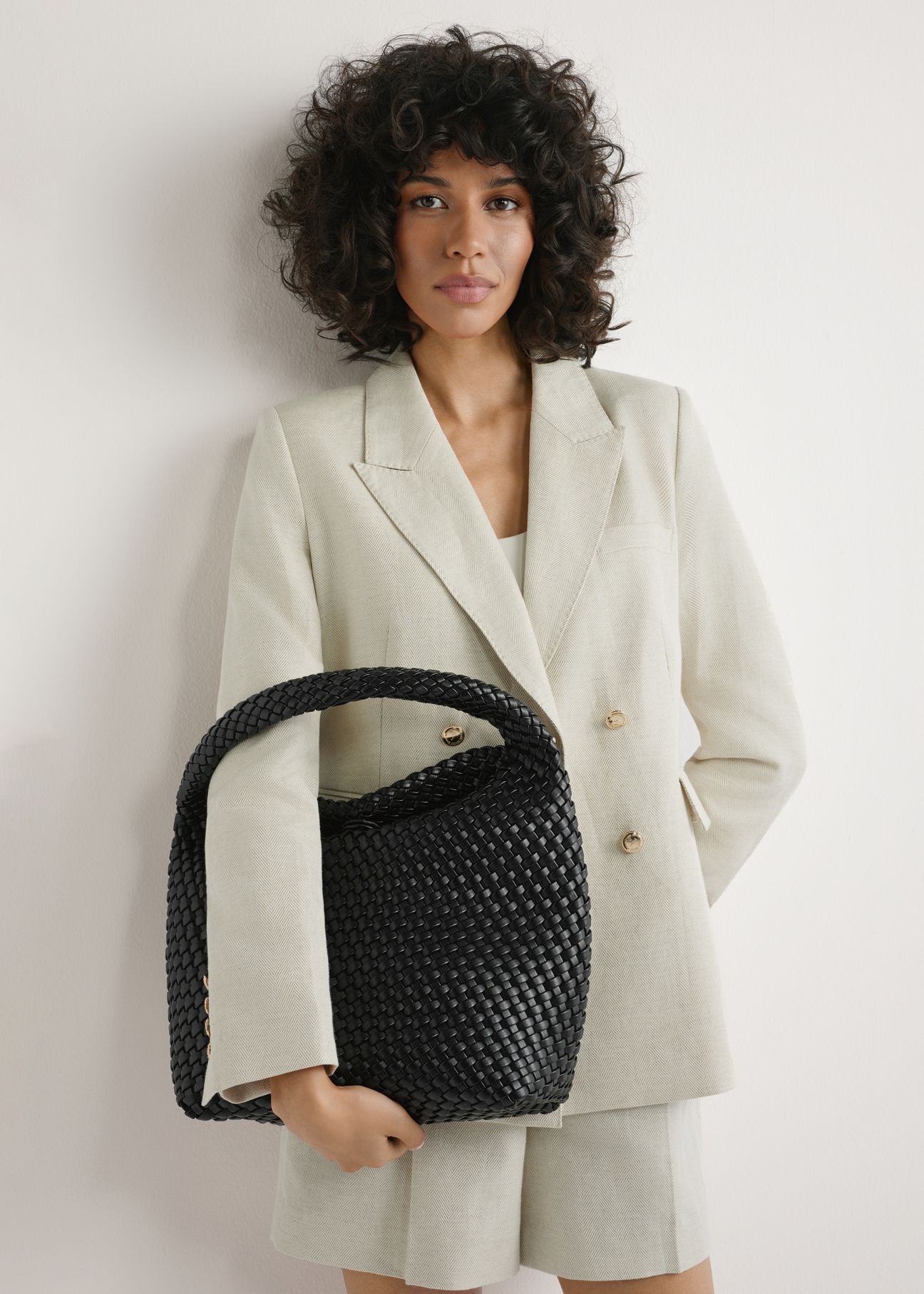 Czarna pleciona torebka shopper TOREC-1148-99(W26) - widok produktu, trzymanego przez modelkę w ręku, na jasnym tle. Widoczna połowa sylwetki. 