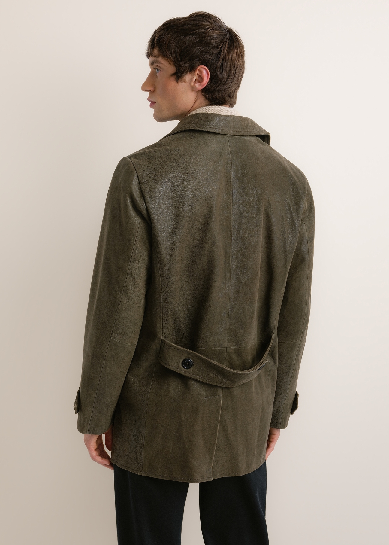 Skórzany płaszcz męski w kolorze khaki KURMS-0409A-8D(Z26), widok produktu z tyłu na modelu. Widoczna połowa sylwetki.