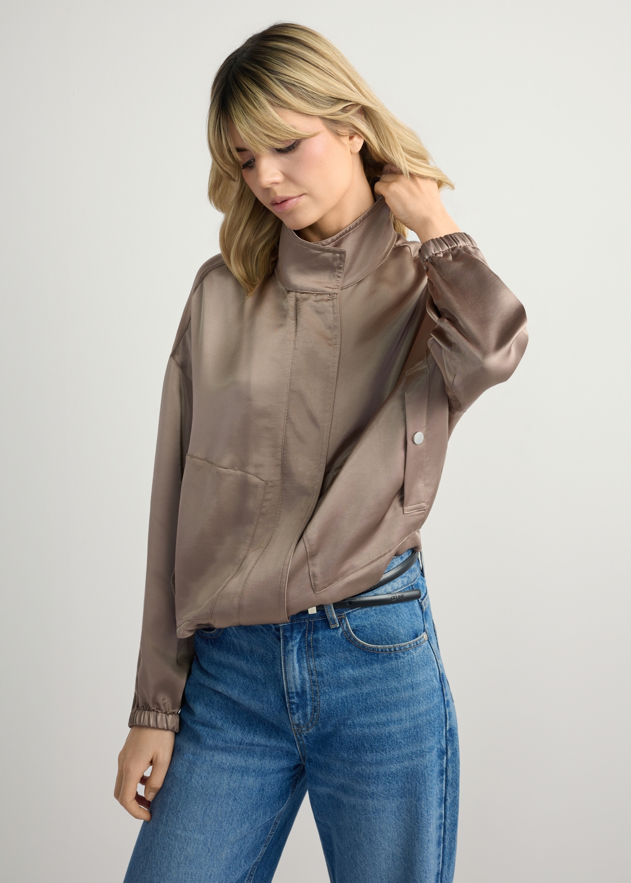 Lekka beżowa bomberka damska KURDT-0627-1K(W26) - widok produktu z przodu, na modelce, na jasnym tle. Widoczna sylwetka do połowy.