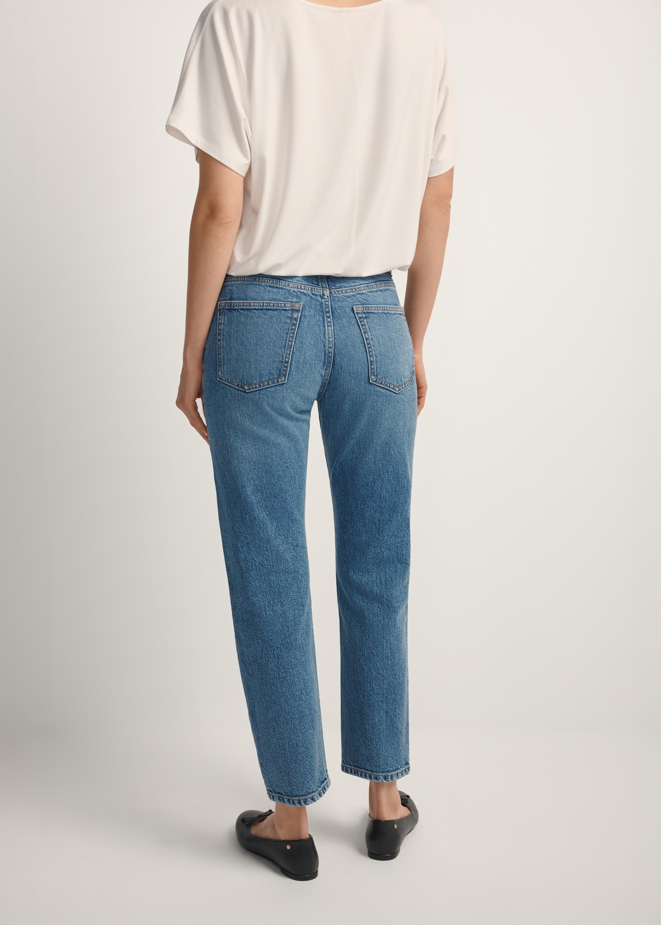 Ciemnoniebieskie spodnie jeansowe damskie JEADT-0011-7C(W26), widok produktu z tyłu na modelce. Widoczna połowa sylwetki.