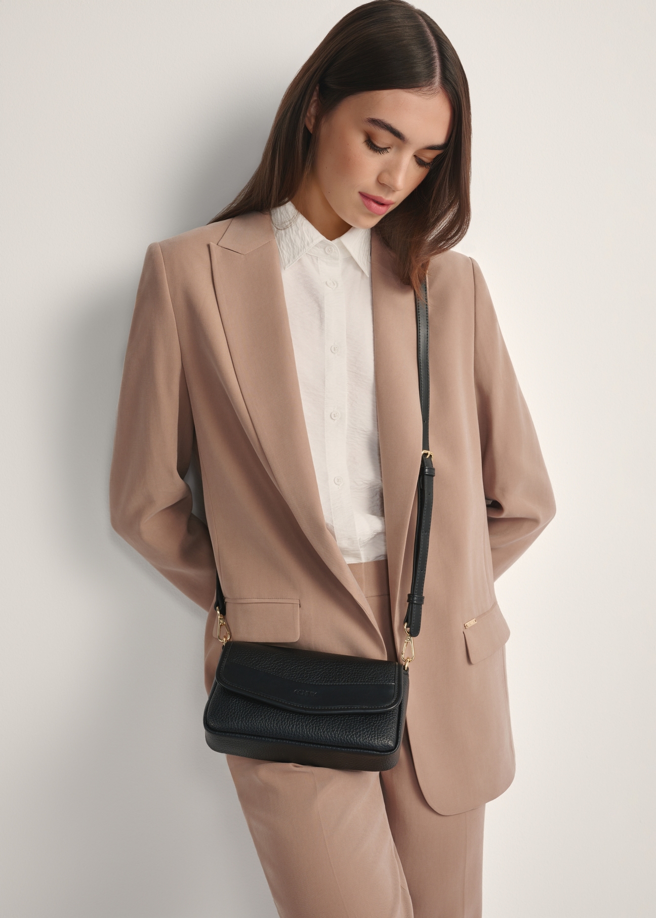 Mała czarna torebka damska TOREC-1163-99(W26), widok produktu od przodu na modelce, widoczna połowa sylwetki.