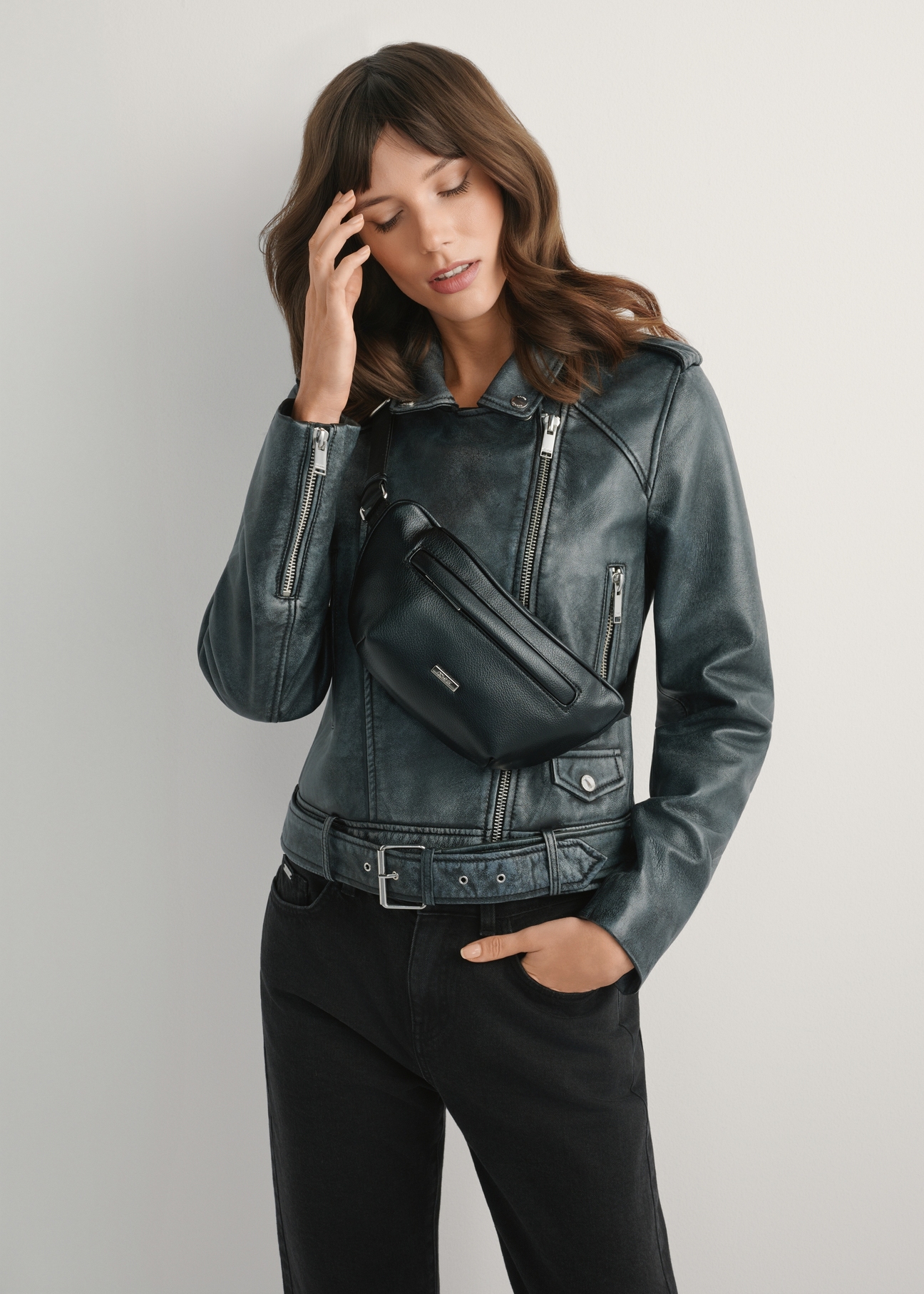 Czarna nerka damska z imitacji skóry TOREC-1194-99(W26) - widok produktu z przodu, na modelce, na jasnym tle. Widoczna sylwetka do kolan. 