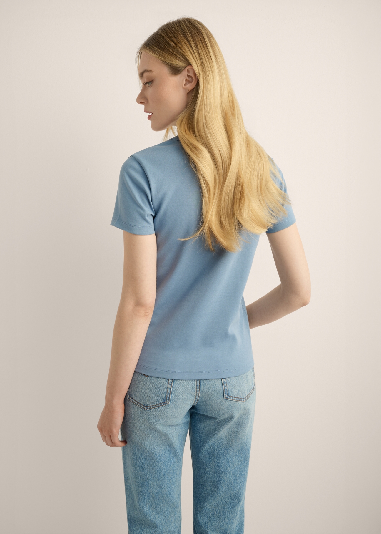 Niebieski bawełniany T-shirt damski TSHDT-0144-7B(Z26). Widok produktu z tyłu na modelce. Widoczna połowa sylwetki.
