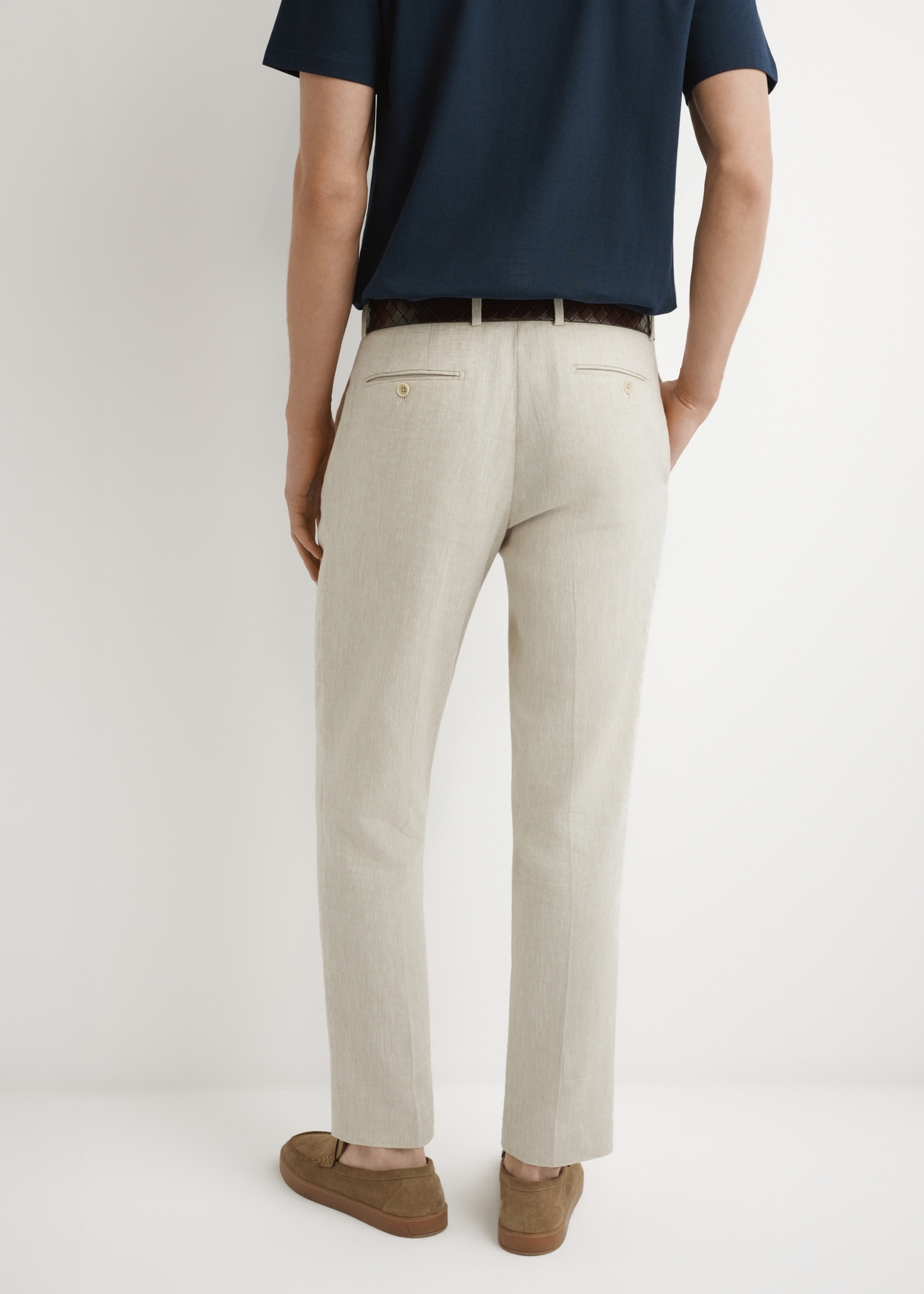 Beżowe spodnie garniturowe męskie w jodełkę SPOMT-0117-1B(W26), widok produktu z tyłu na modelu. Widoczna połowa sylwetki.