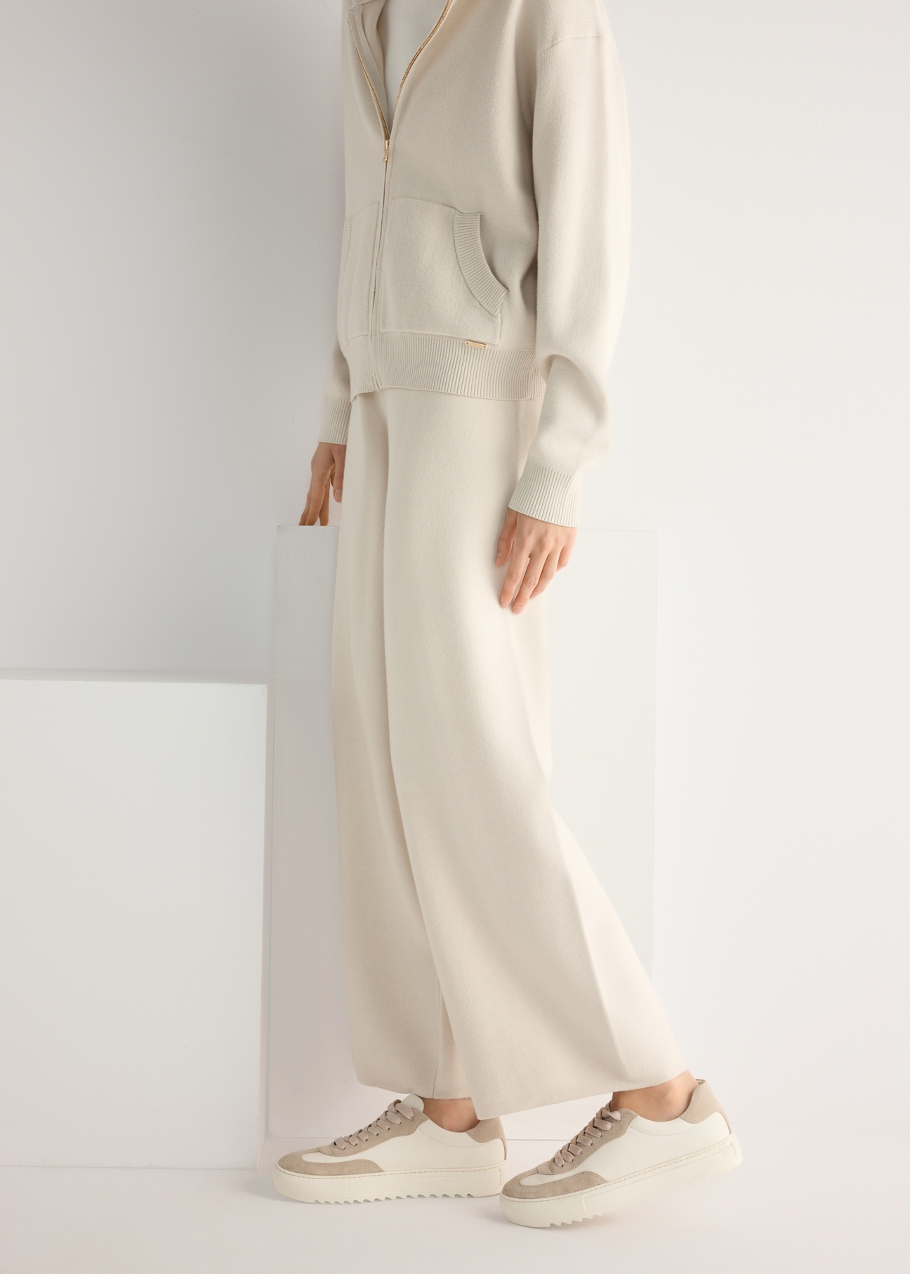 Skórzane tenisówki damskie w kolorze kremowym BUTYD-1260-0B(W26), widok produktu od boku na modelce, widoczna połowa sylwetki.