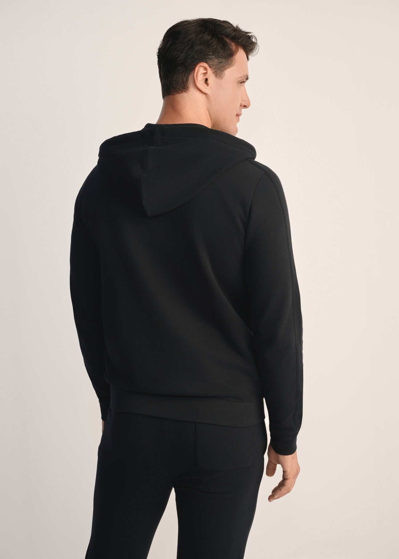 Czarna bluza męska z kapturem BLZMT-0074-99(Z25), widok produktu z tyłu na modelu. Widoczna połowa sylwetki.
