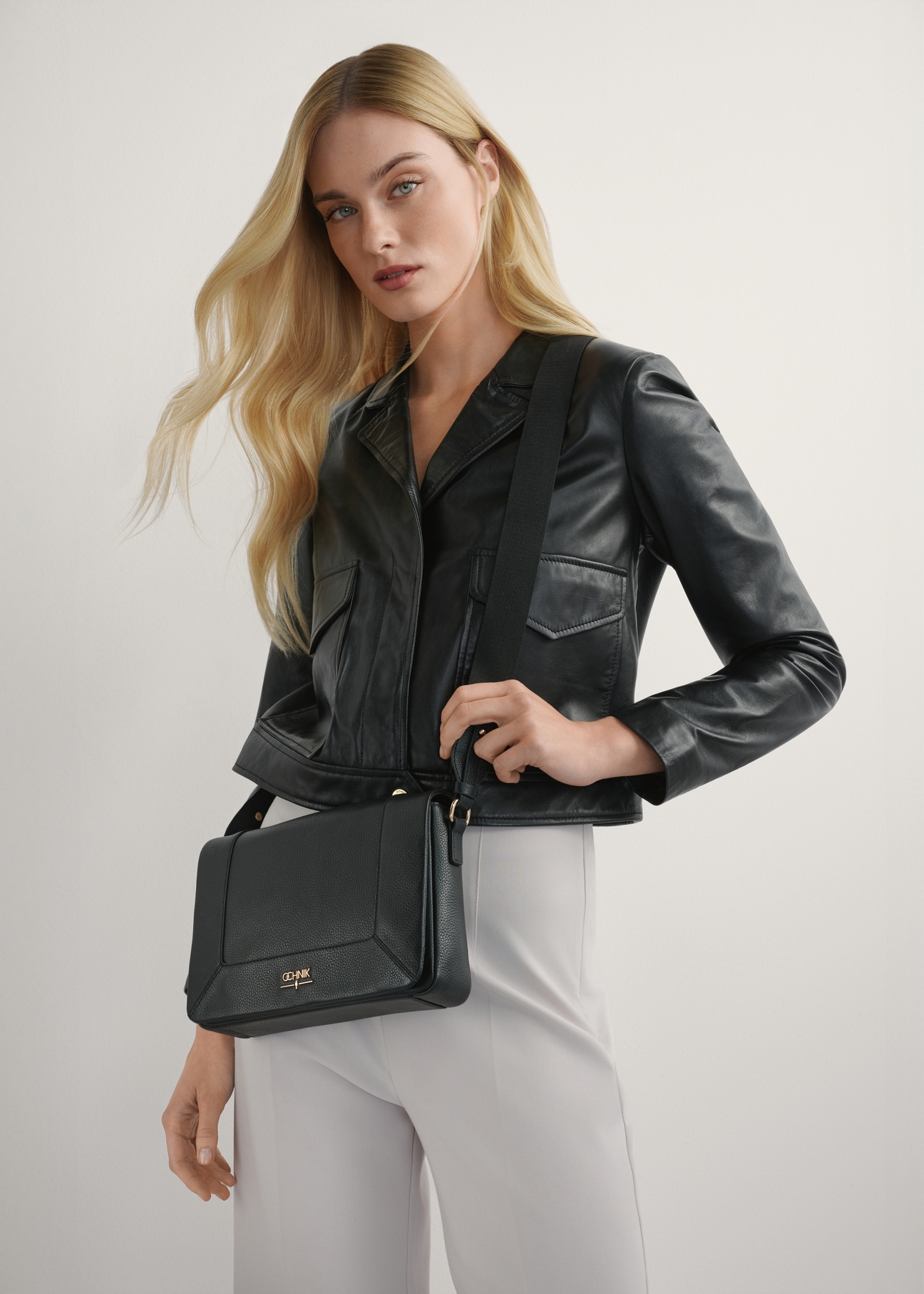 Czarna skórzana torebka listonoszka TORES-1266-9I(W26) - widok produktu z przodu, na modelce, na jasnym tle. 