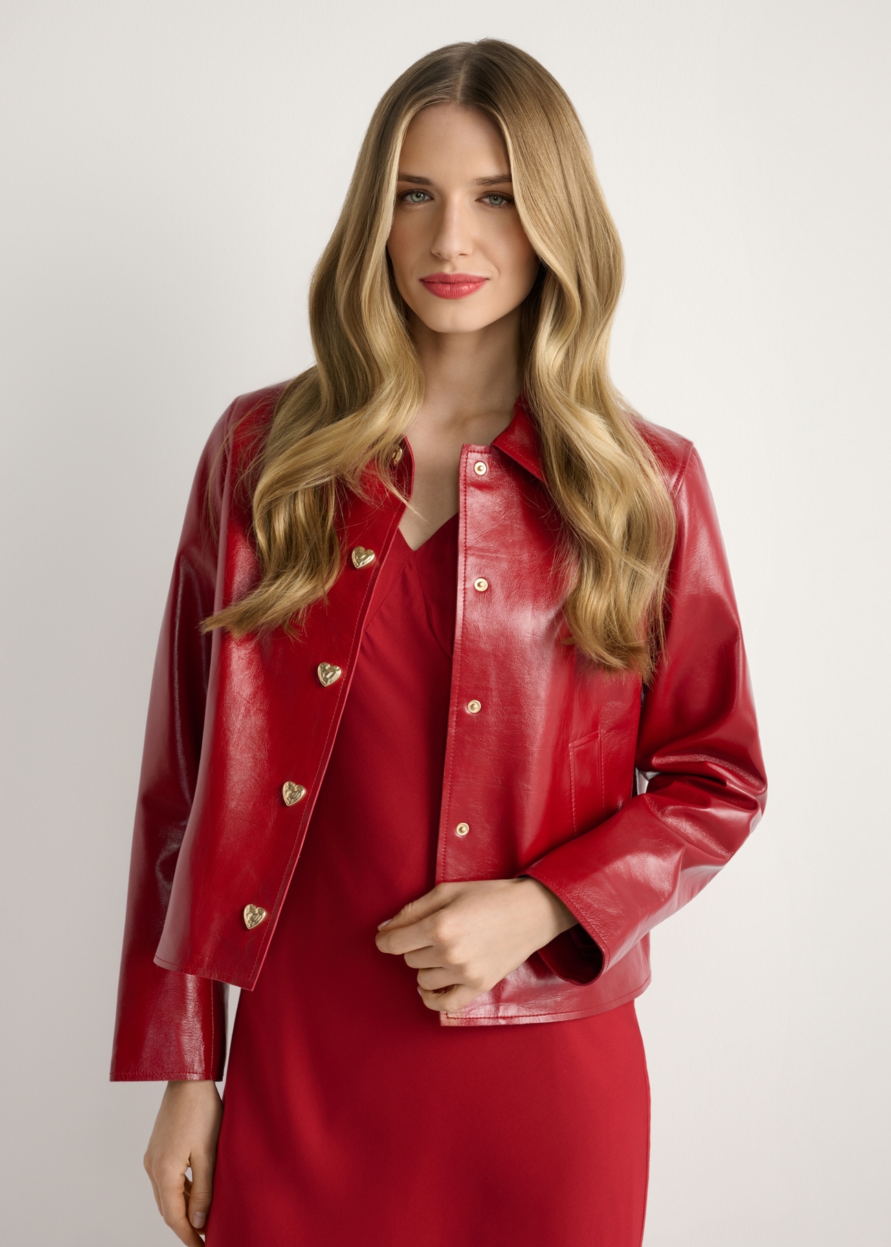 Czerwona krótka kurtka damska KURDS-0612-4B(W26), widok produktu od przodu na modelce, widoczna połowa sylwetki.