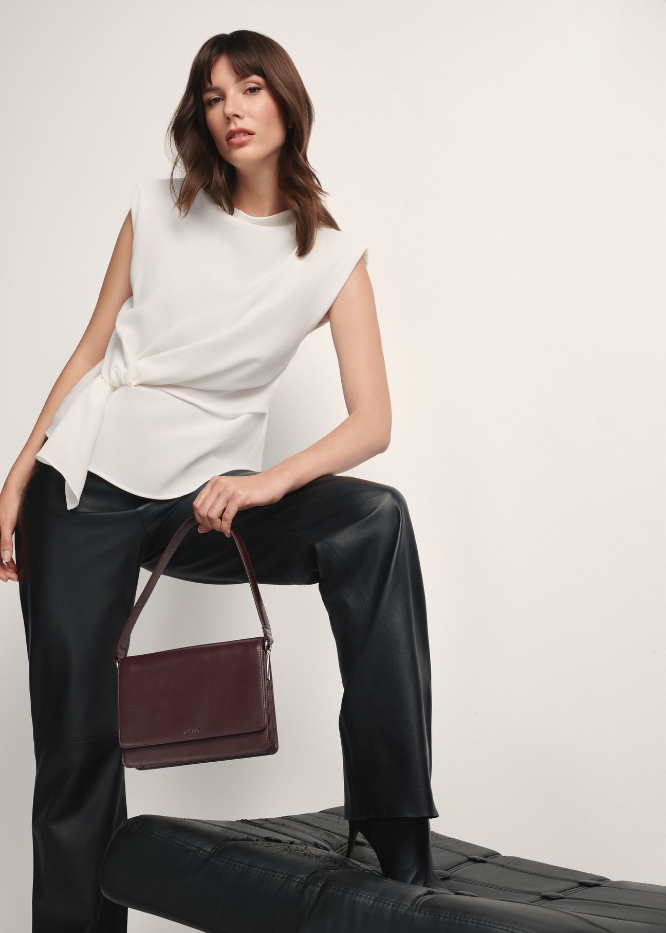 Skórzana torebka damska w kolorze bordowym TORES-1189-49(Z25), widok produktu w dłoni modelki na jasnym tle.