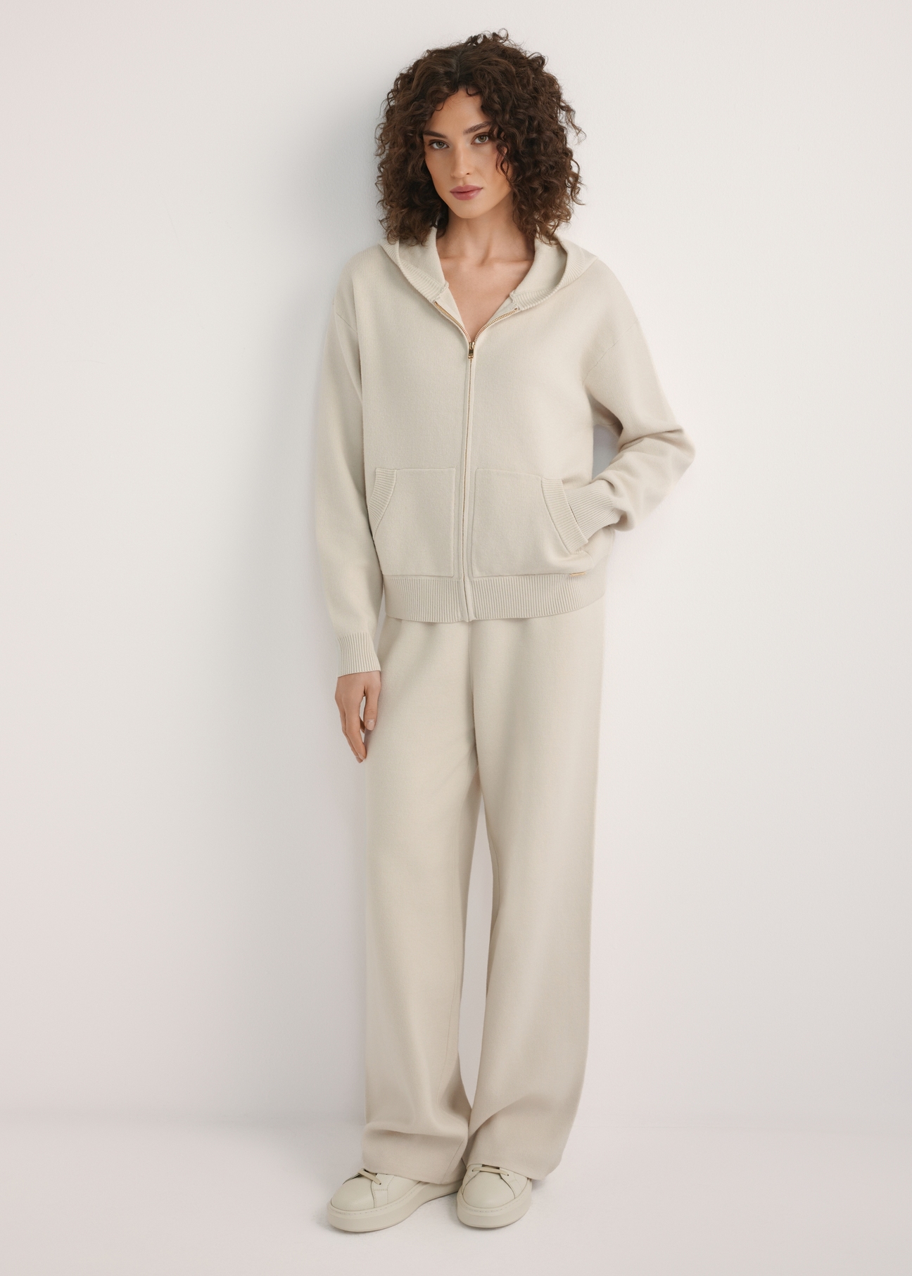 Beżowa bluza damska z kapturem BLZDT-0120-1A(W26), widok produktu z przodu na modelce. Widoczna cała sylwetka.