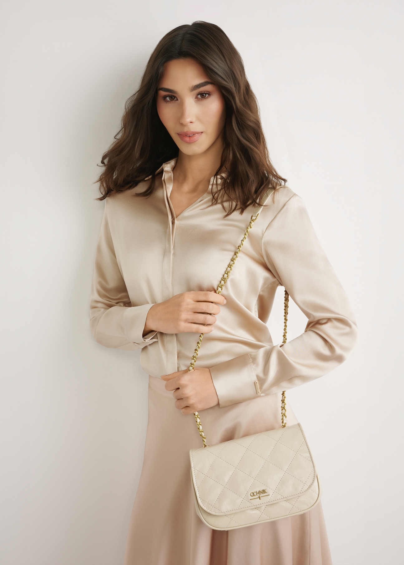 Kremowa skórzana lakierowana torebka damska TORES-1297-0B(W26), widok produktu z przodu na modelce. Widoczna sylwetka do kolan. 