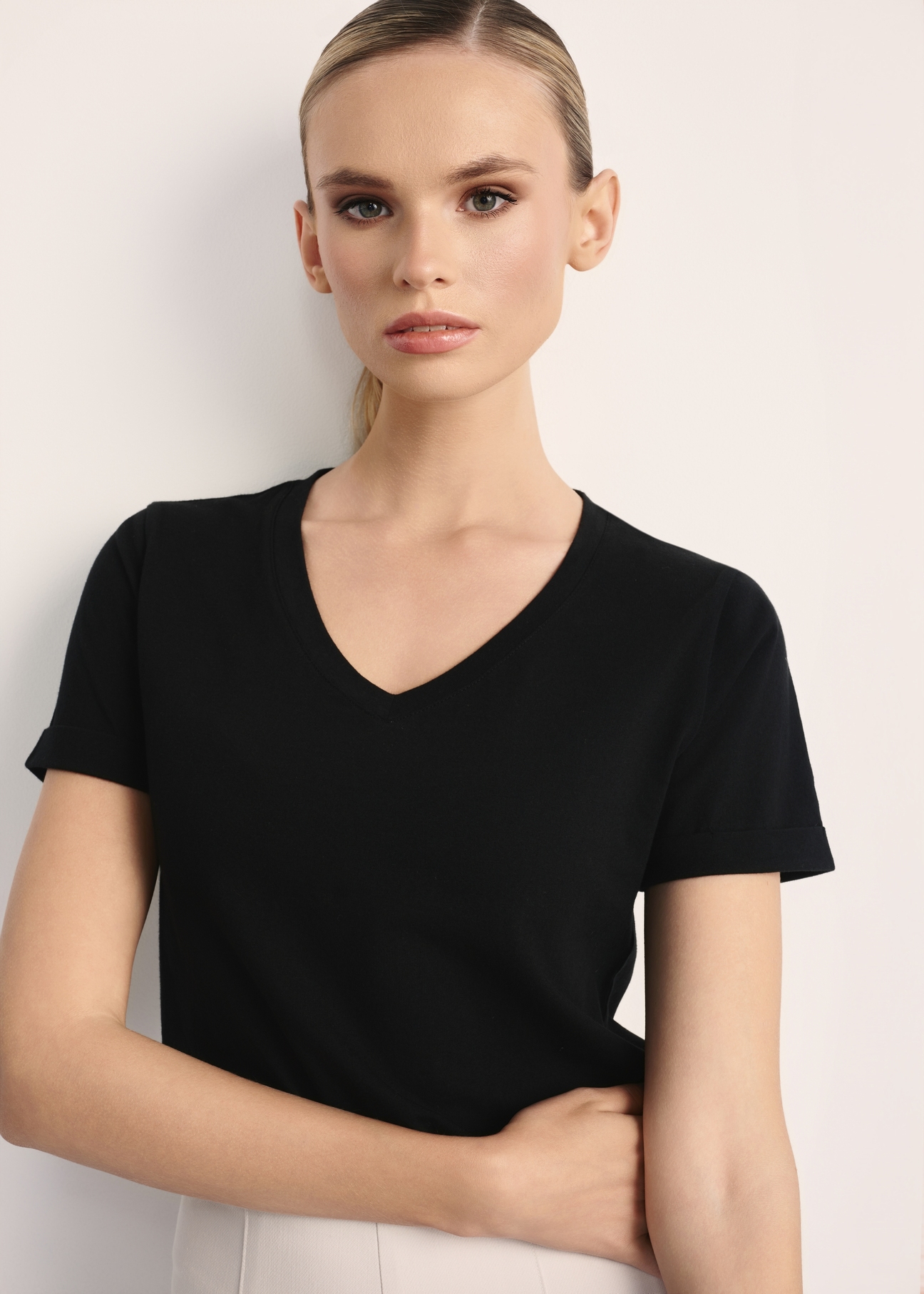 Czarny T-shirt damski w serek TSHDT-0118A-99(Z25), widok produktu z przodu na modelce. Widoczna połowa sylwetki.