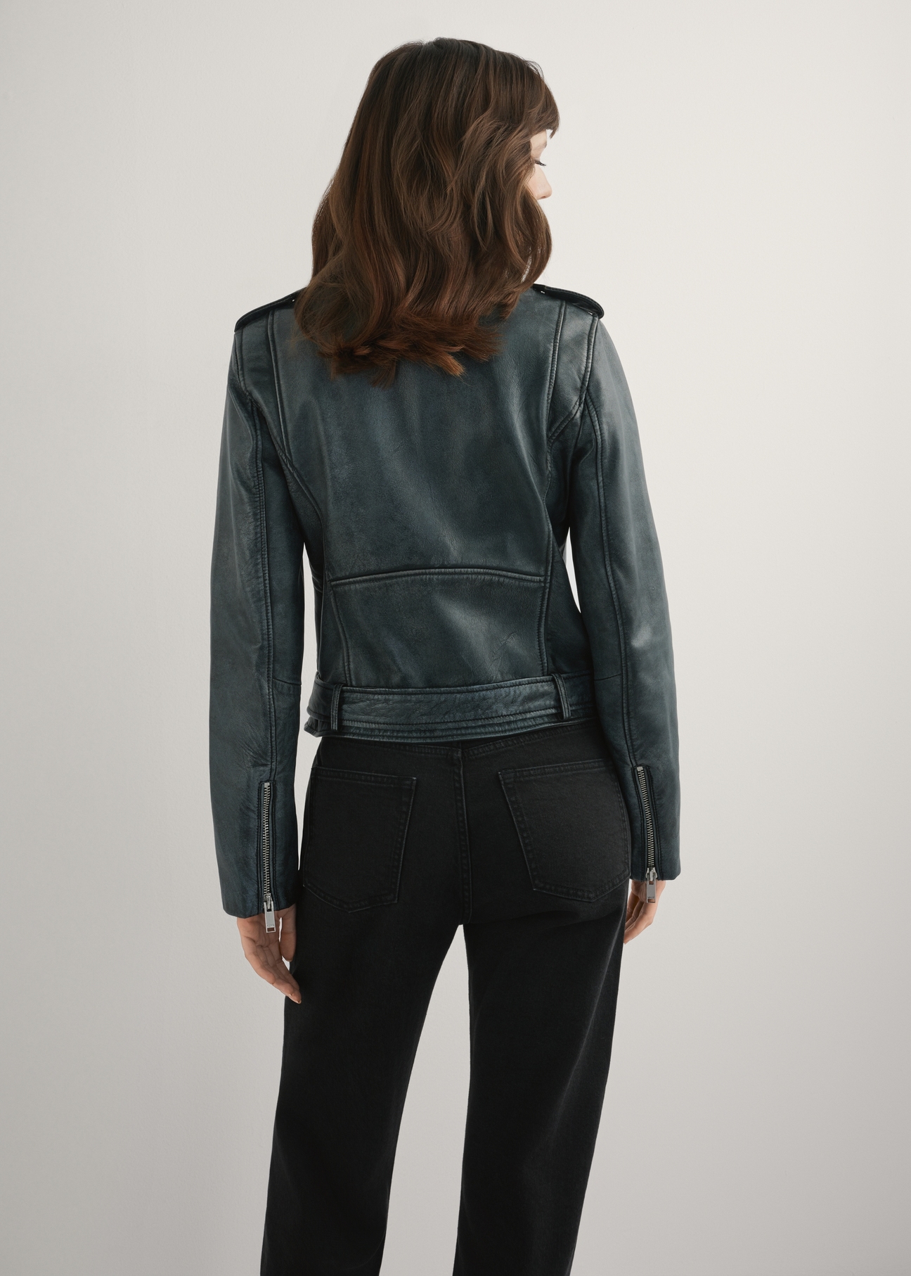 Skórzana kurtka damska w kolorze szarym KURDS-0371-9D(W26), widok produktu z tyłu na modelce. Widoczna połowa sylwetki.