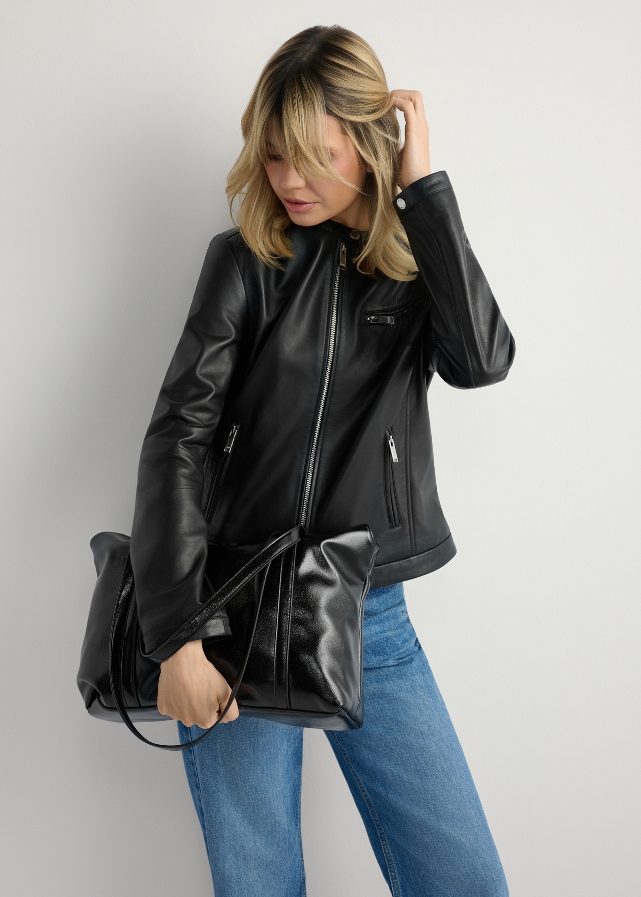 Czarna torebka shopper damska TOREC-1206-9F(W26), widok produktu w dłoni modelki. Widoczna połowa sylwetki.