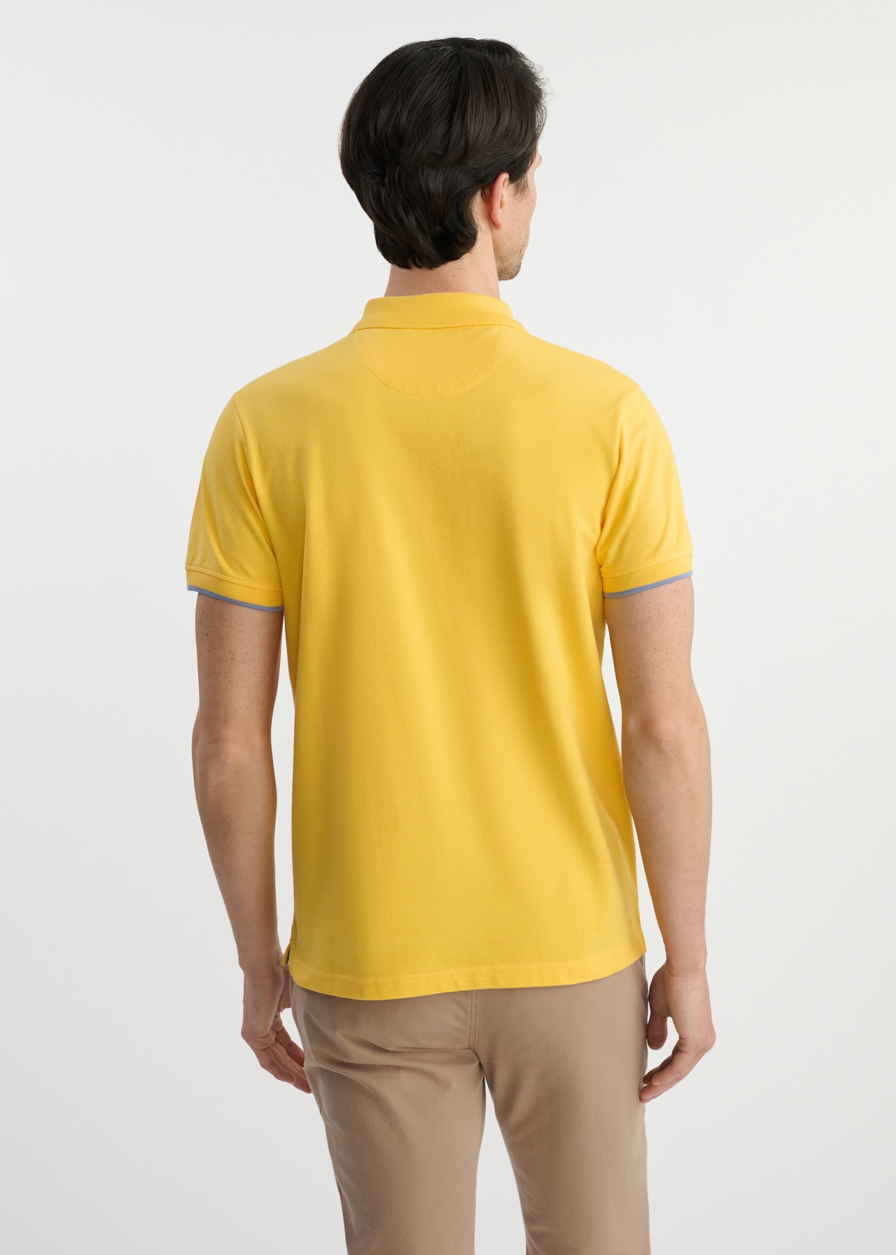 Żółta koszulka polo z bawełny POLMT-0045B-22(W25) - widok z tyłu na modelu na białym tle. Widoczna połowa sylwetki. 