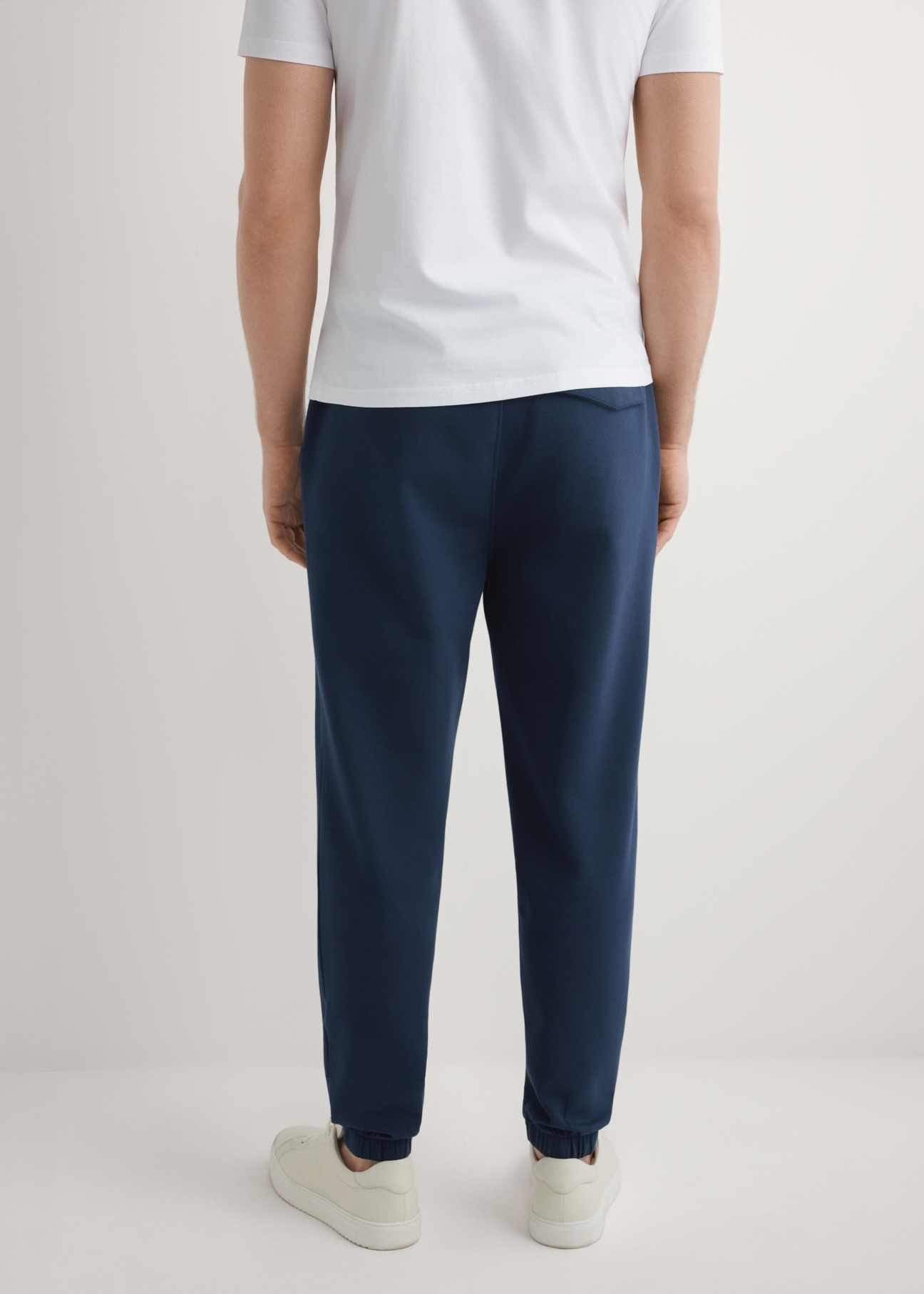 Granatowe męskie spodnie dresowe SPOMT-0109-7E(W26), widok produktu z tyłu na modelu. Widoczna połowa sylwetki.