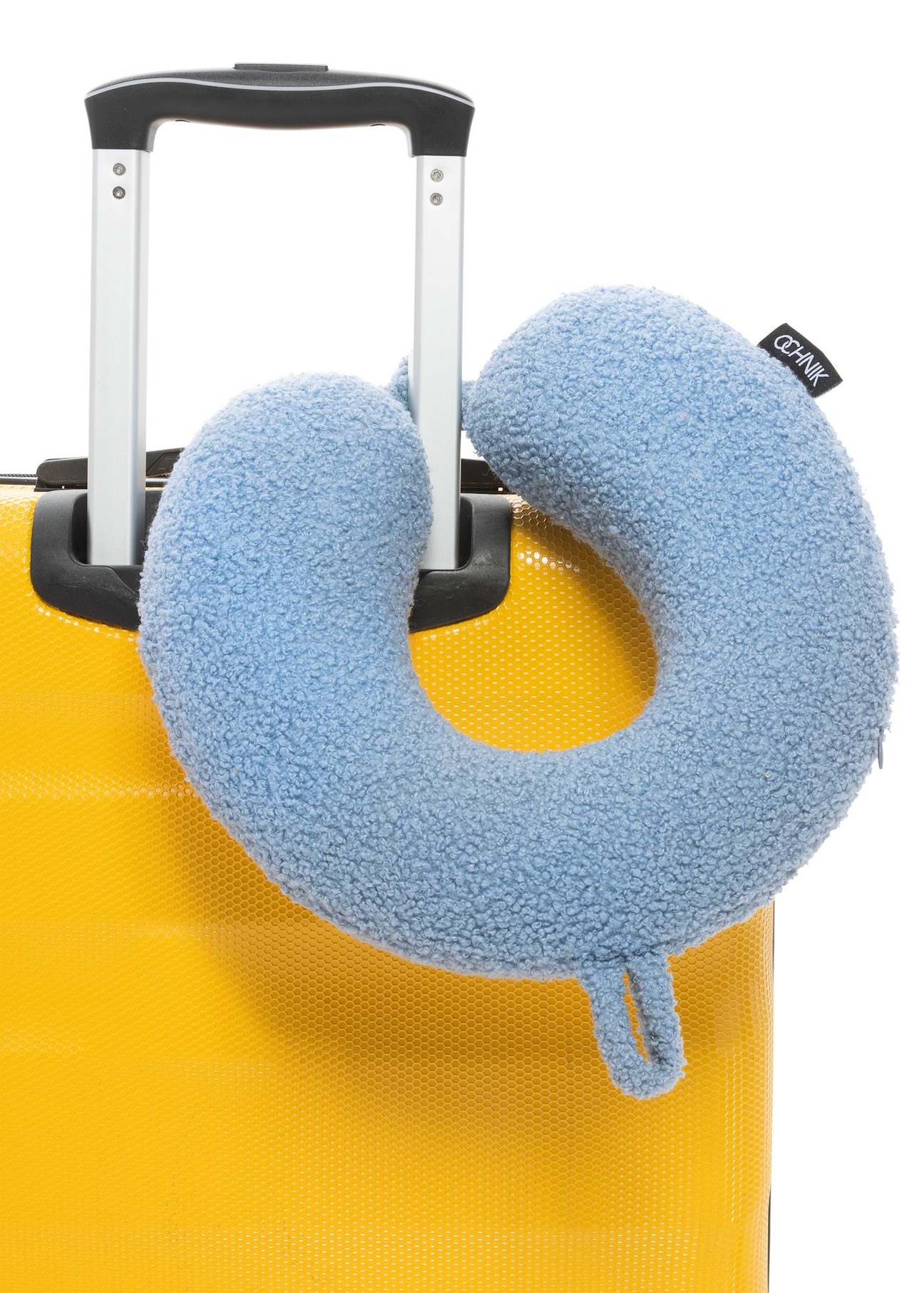 Miękki błękitny podgłówek AW-014-0003-61(W25), widok produktu na walizce na białym tle.