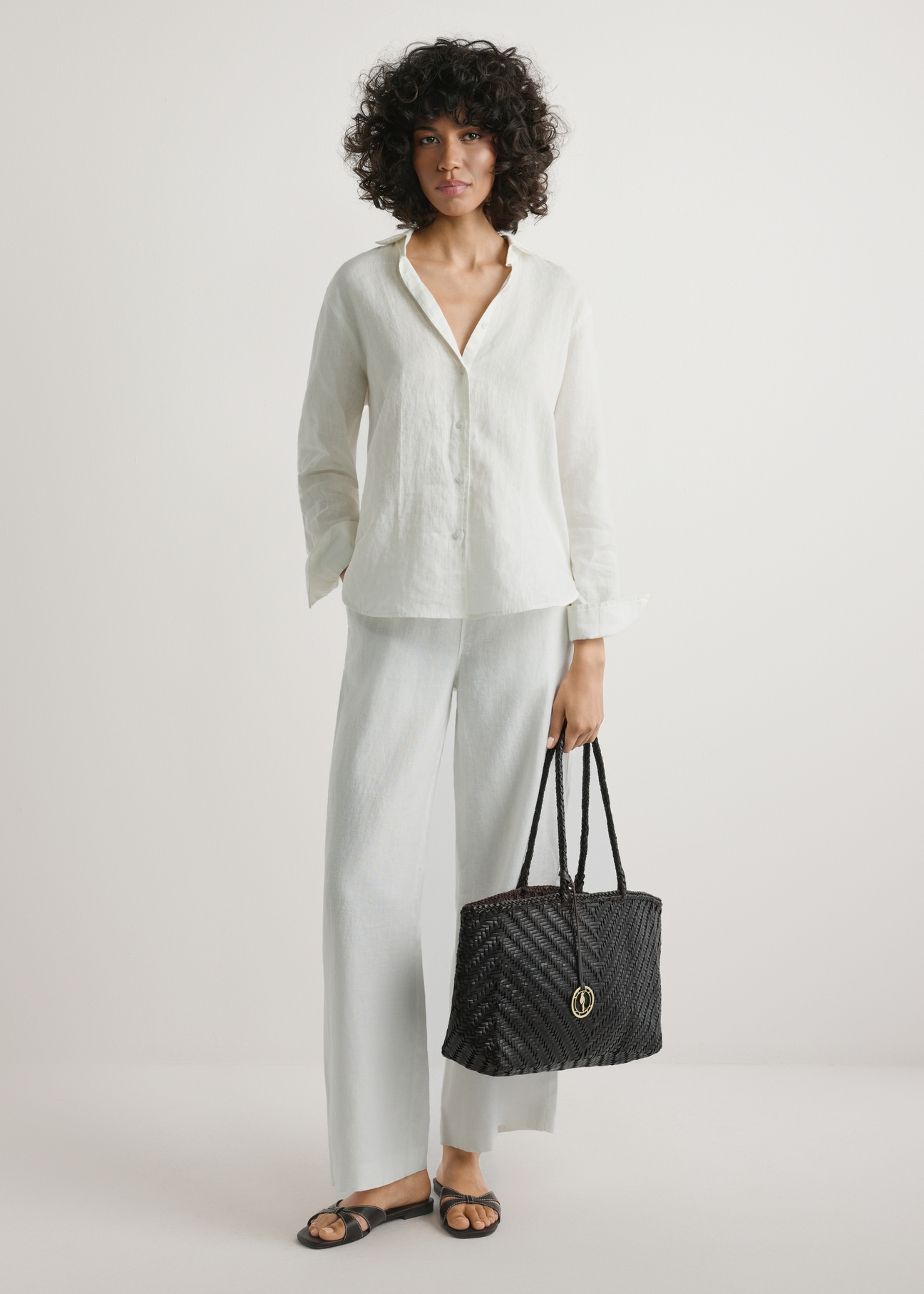 Ciemnobrązowa pleciona torebka damska TORES-1301-1I(W26), widok produktu w dłoni modelki. Widoczna cała sylwetka.