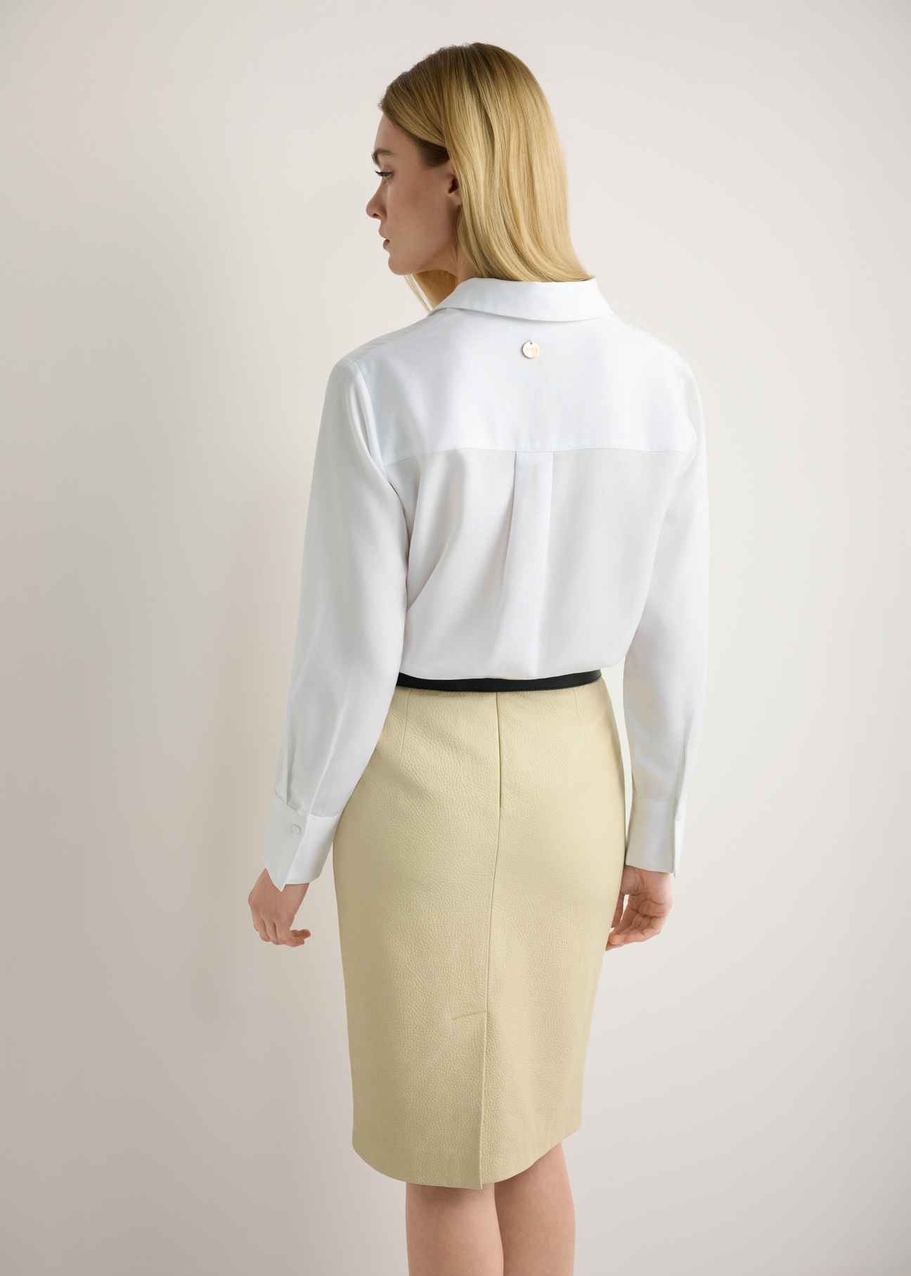 Biała koszula damska KOSDT-0182-0A(W26), widok produktu z tyłu na modelce. Widoczna połowa sylwetki.