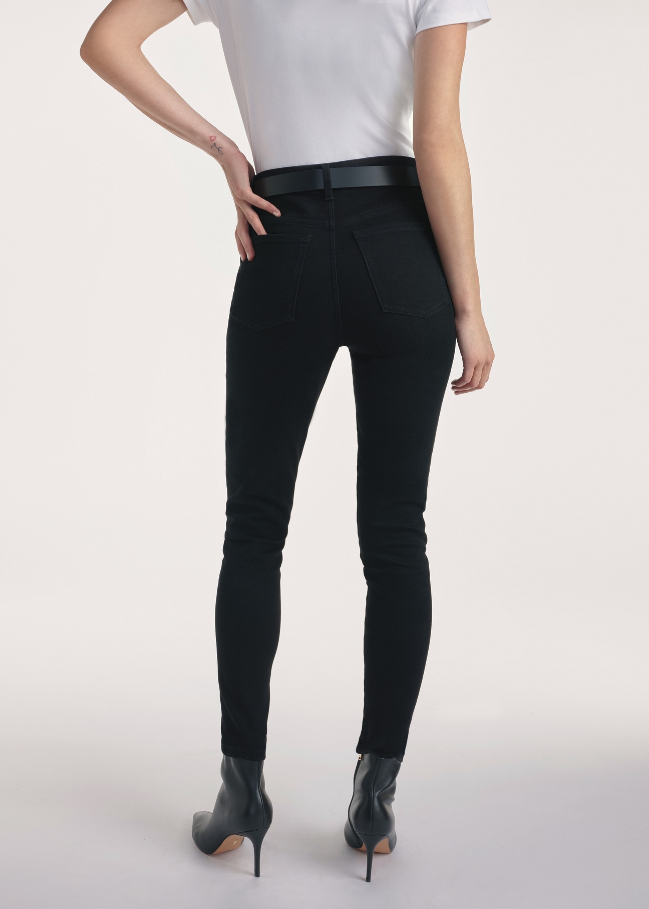 Czarne jeansowe spodnie damskie JEADT-0010A-99(Z25), produkt widoczny z tyłu na modelce, widoczne pół sylwetki.
