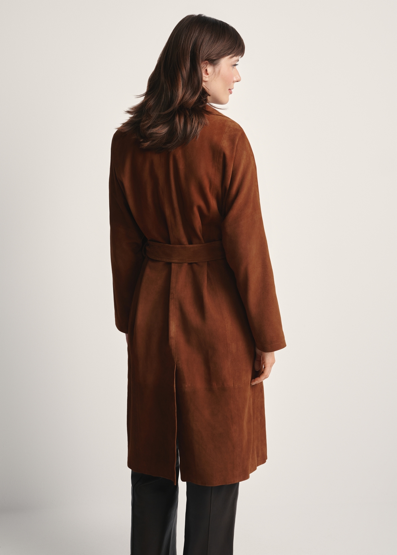 Brązowy zamszowy płaszcz damski oversize KURDS-0551-0775(Z25), widok produktu z tyłu na modelce. Widoczna połowa sylwetki.