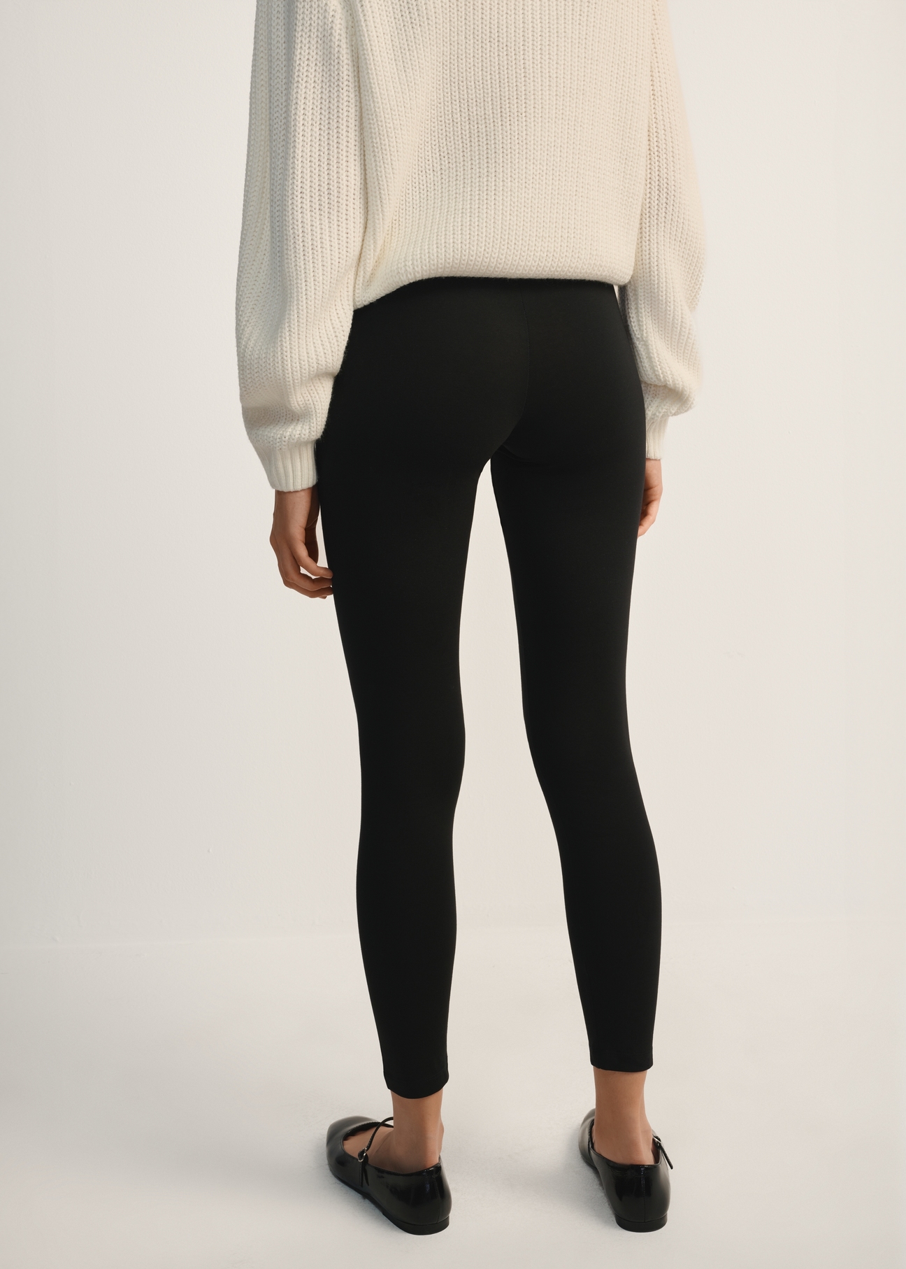 Czarne legginsy damskie LEGDT-0001-99(Z25), widok produktu od tyłu na modelce, widoczna połowa sylwetki.