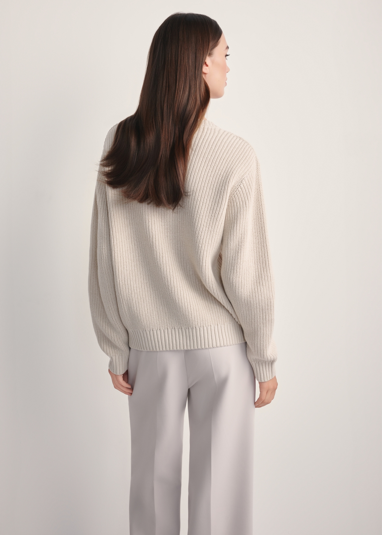 Beżowy sweter damski SWEDT-0238-81(Z25), widok produktu z tyłu na modelce. Widoczna połowa sylwetki.