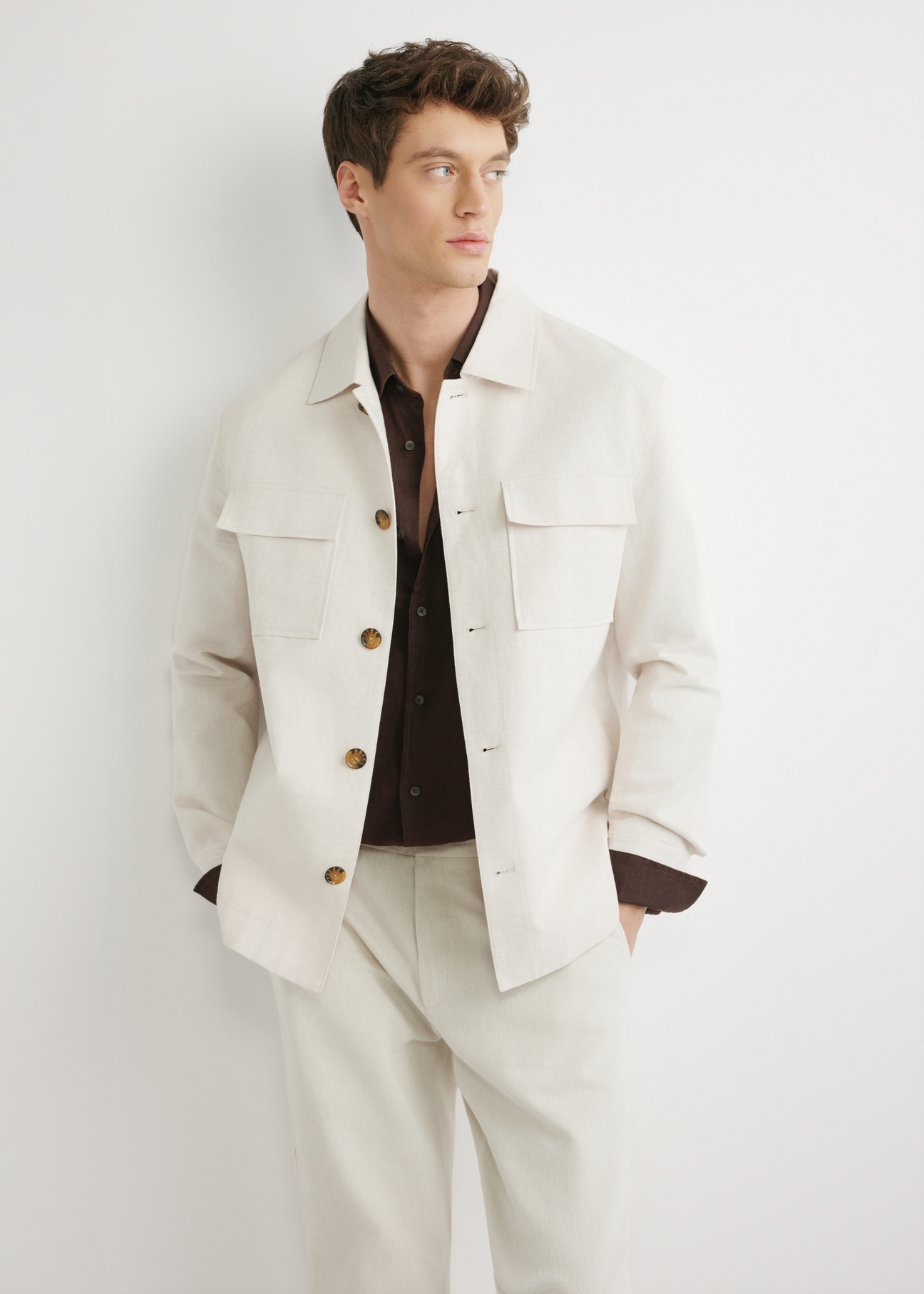 Jasnobeżowa lniana kurtka męska KURMT-0420-1A(W26) - widok produktu z przodu, na modelu, na jasnym tle. Widoczna połowa sylwetki. 