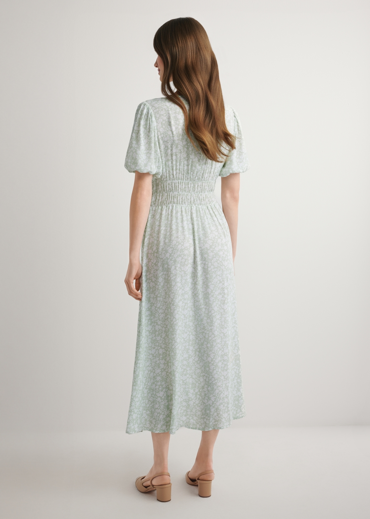 Długa sukienka w kwiaty w kolorze szałwiowym SUKDT-0191-8P(W26), widok produktu z tyłu na modelce. Widoczna cała sylwetka.