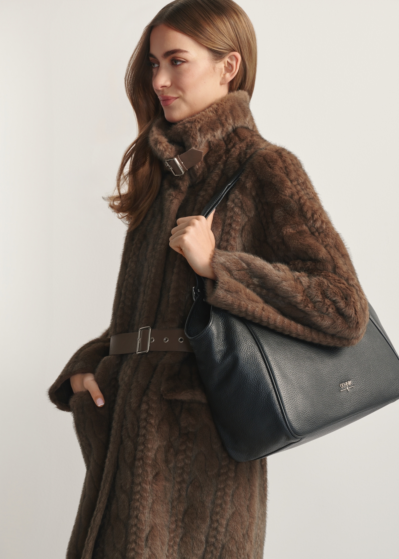 Czarna skórzana duża torebka damska TORES-1042D-99(Z25) - widok produktu z boku, na modelce, na jasnym tle. Widoczna połowa sylwetki.