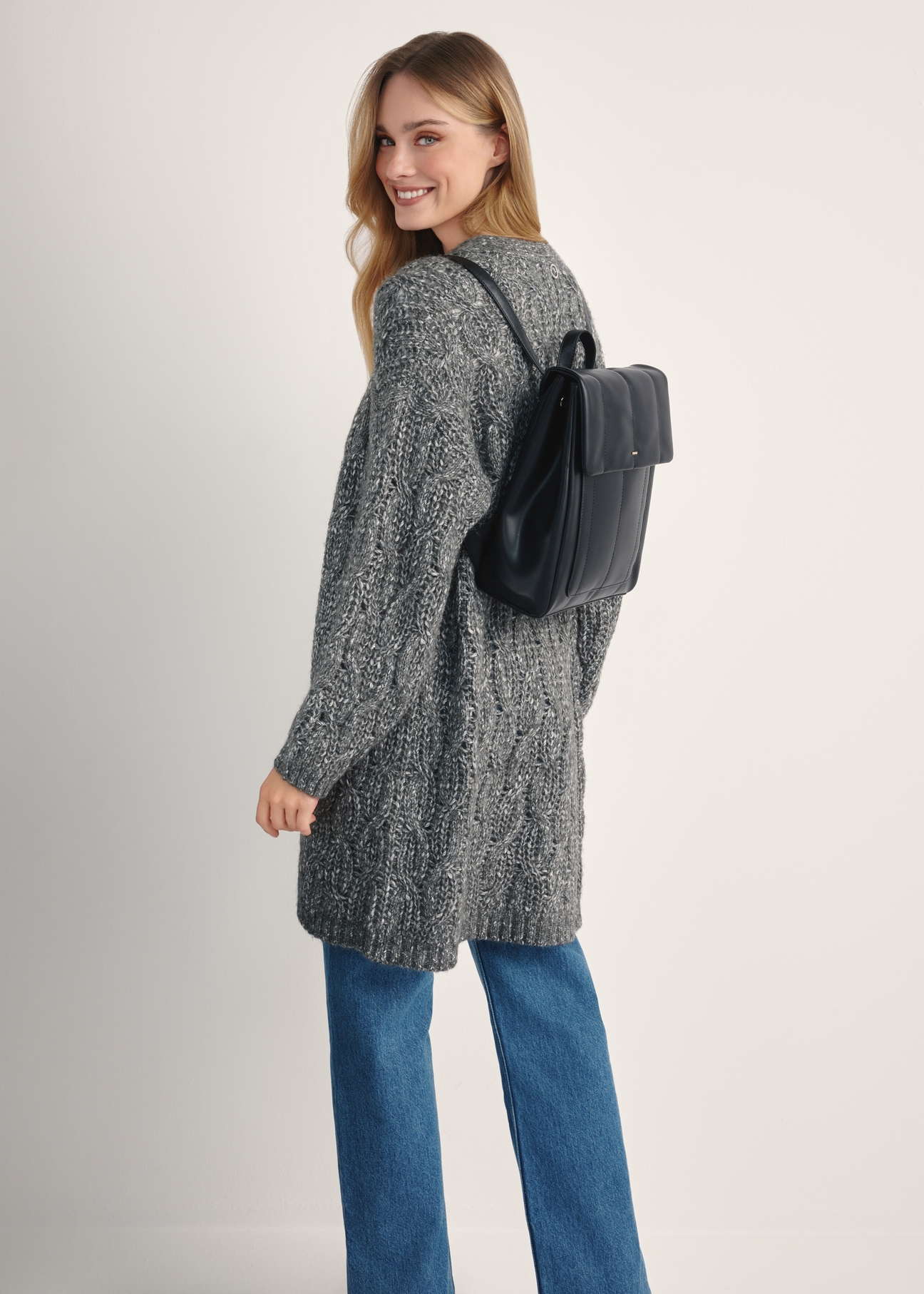 Czarny elegancki plecak damski TOREC-1105-99(Z25) - widok produktu z przodu na modelce na białym tle. Widoczna cała sylwetka tyłem.