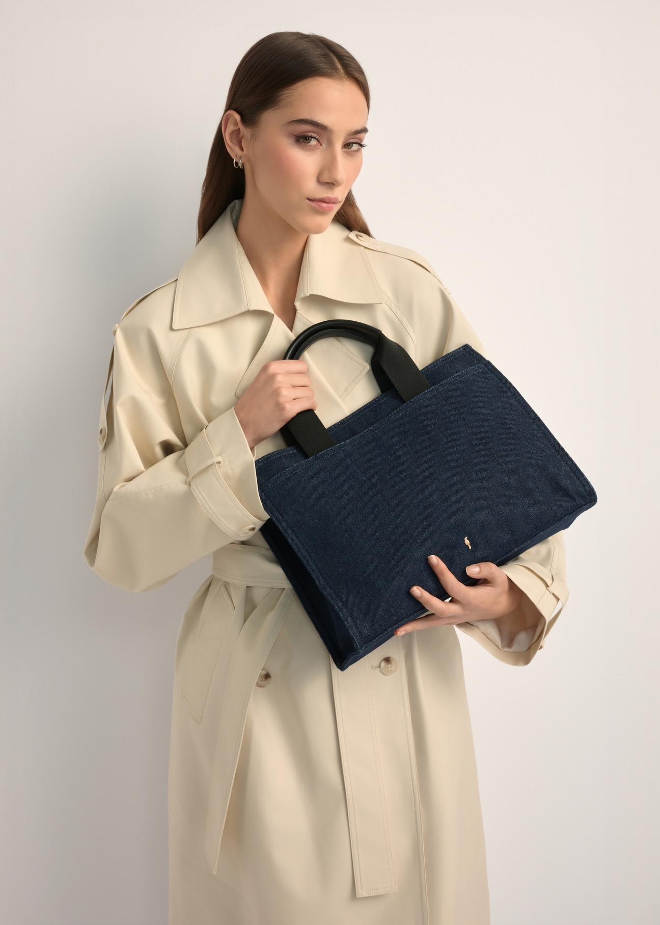 Granatowa jeansowa torebka damska TOREN-0332-7H(W26), widok produktu w rękach modelki. Widoczna połowa sylwetki.