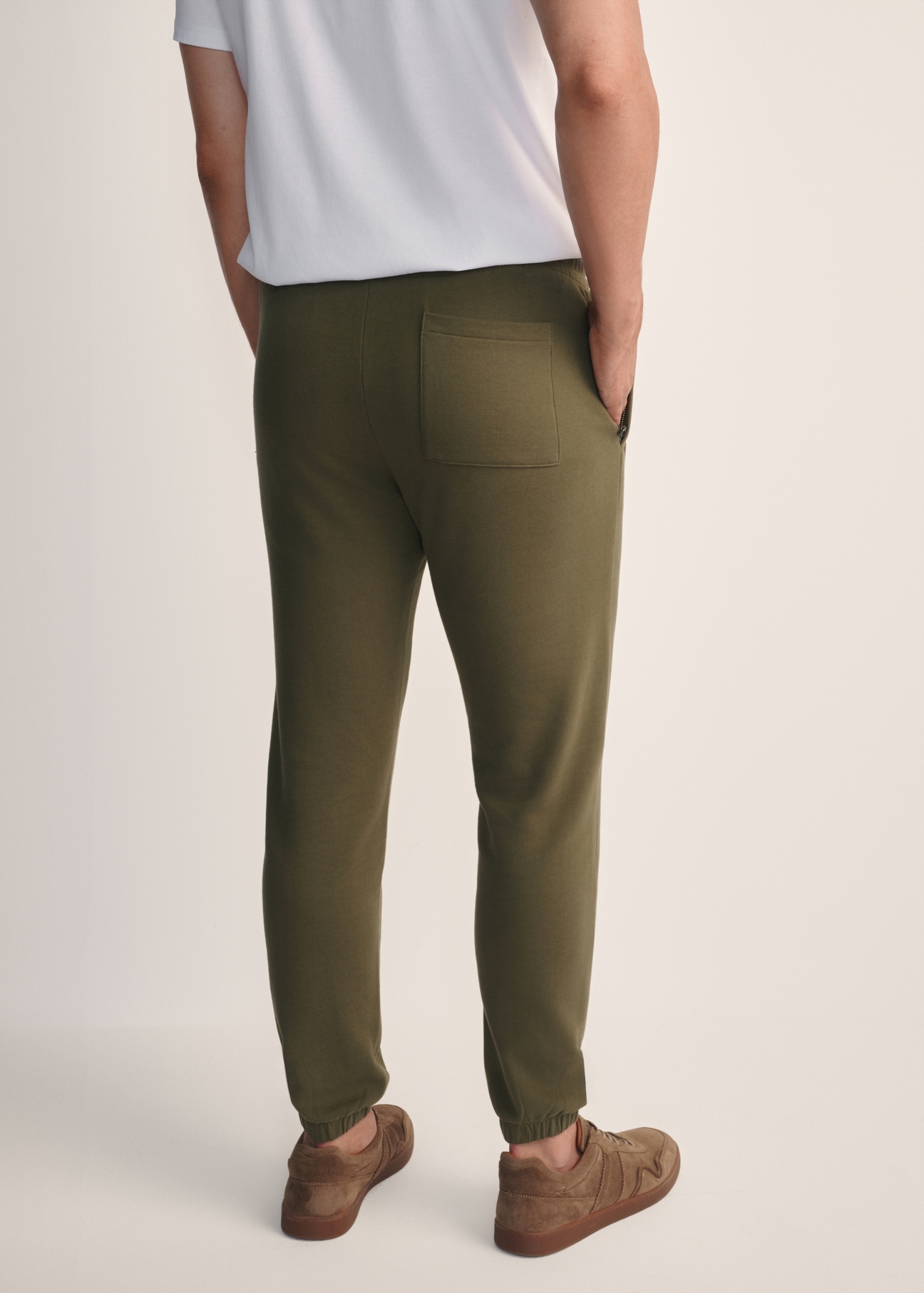Dresowe spodnie męskie w kolorze khaki SPOMT-0101-55(Z25), widok produktu z tyłu na modelu. Widoczna połowa sylwetki.