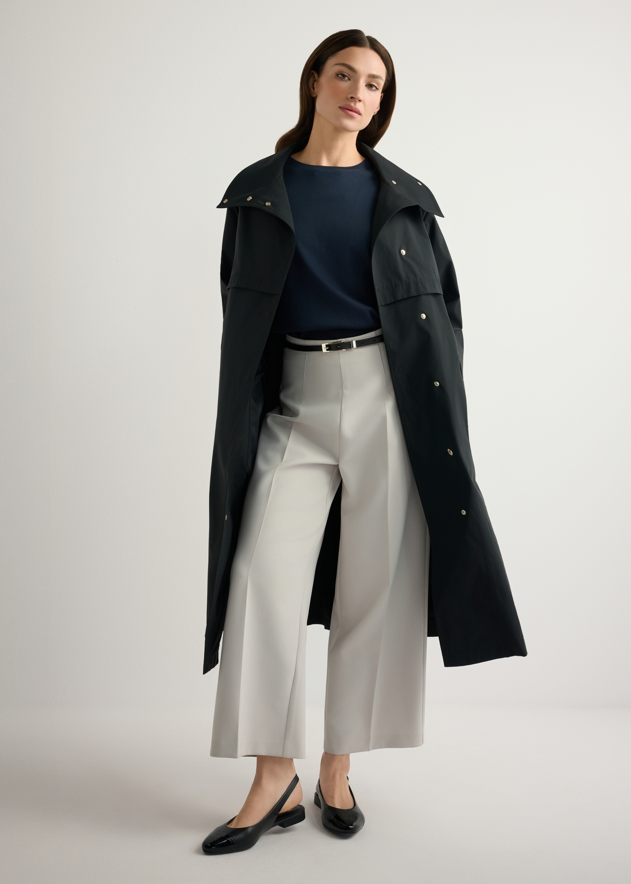 Czarny długi płaszcz damski KURDT-0653-99(W26), widok produktu z przodu na modelce. Widoczna cała sylwetka.