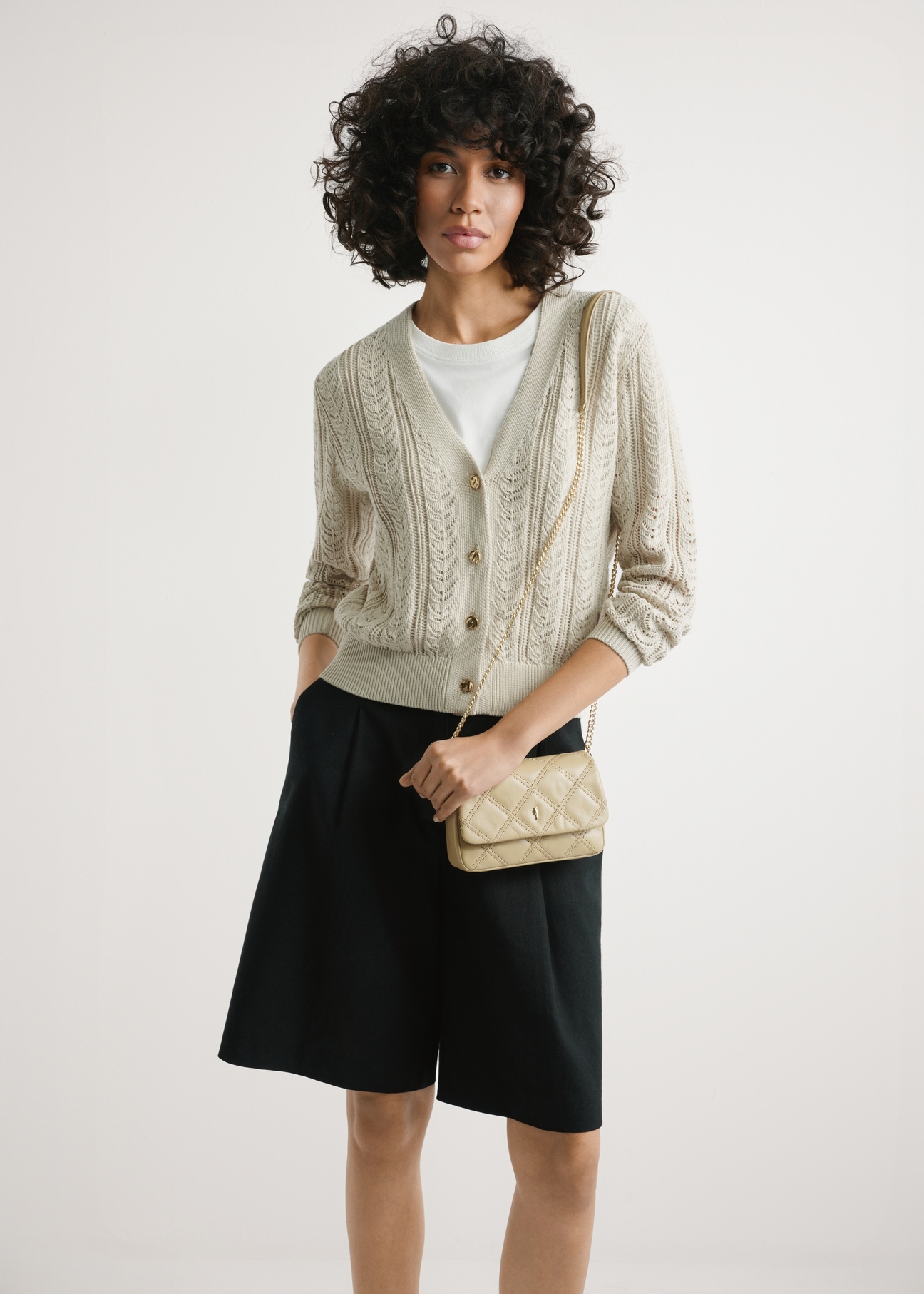 Mała beżowa skórzana torebka damska TORES-1044-1B(W26) - widok produktu z przodu, na modelce, na jasnym tle. Widoczna sylwetka do połowy.