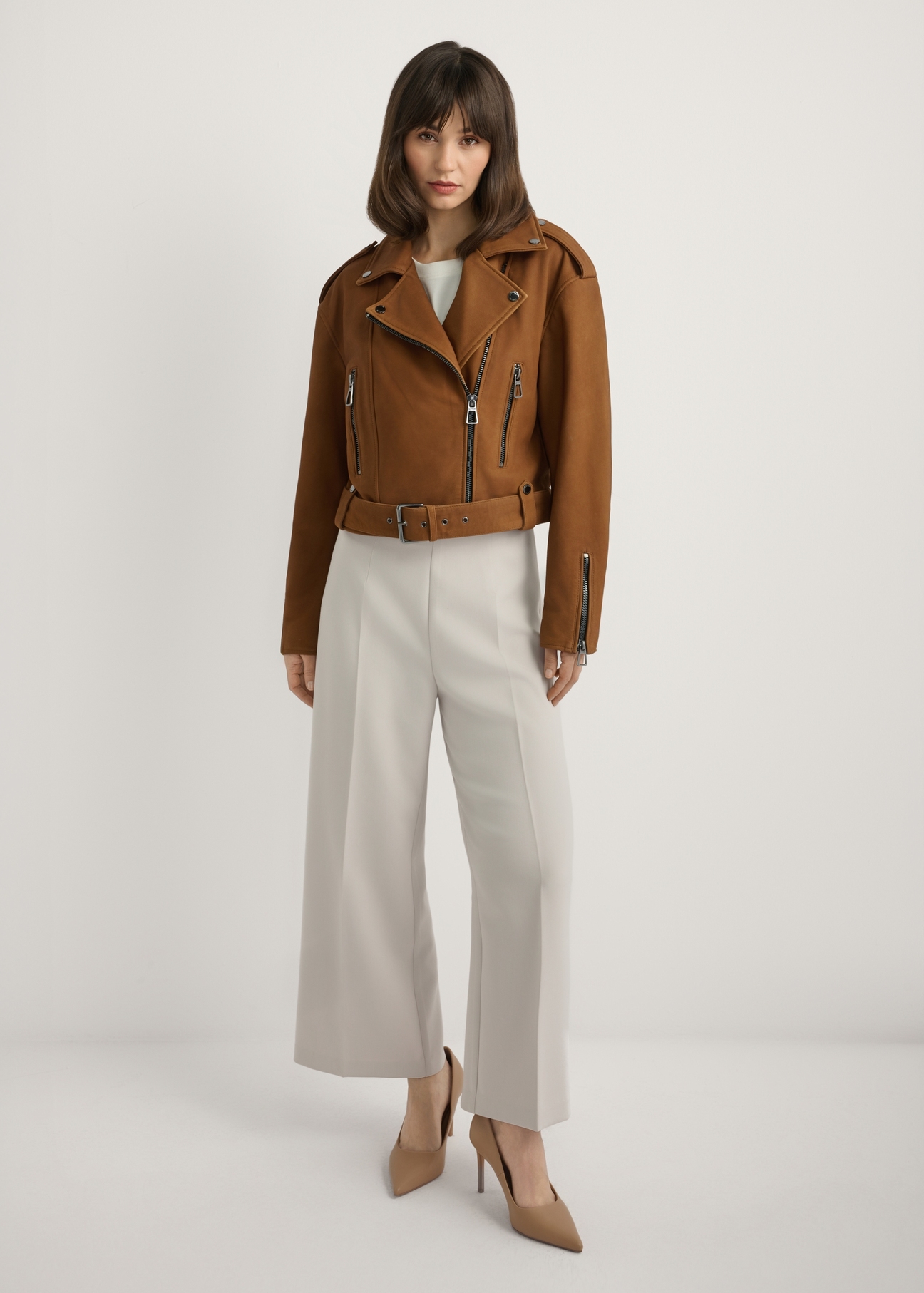 Skórzana kurtka ramoneska w kolorze koniaku KURDS-0610-1F(W26), widok produktu z przodu na modelce. Widoczna cała sylwetka.