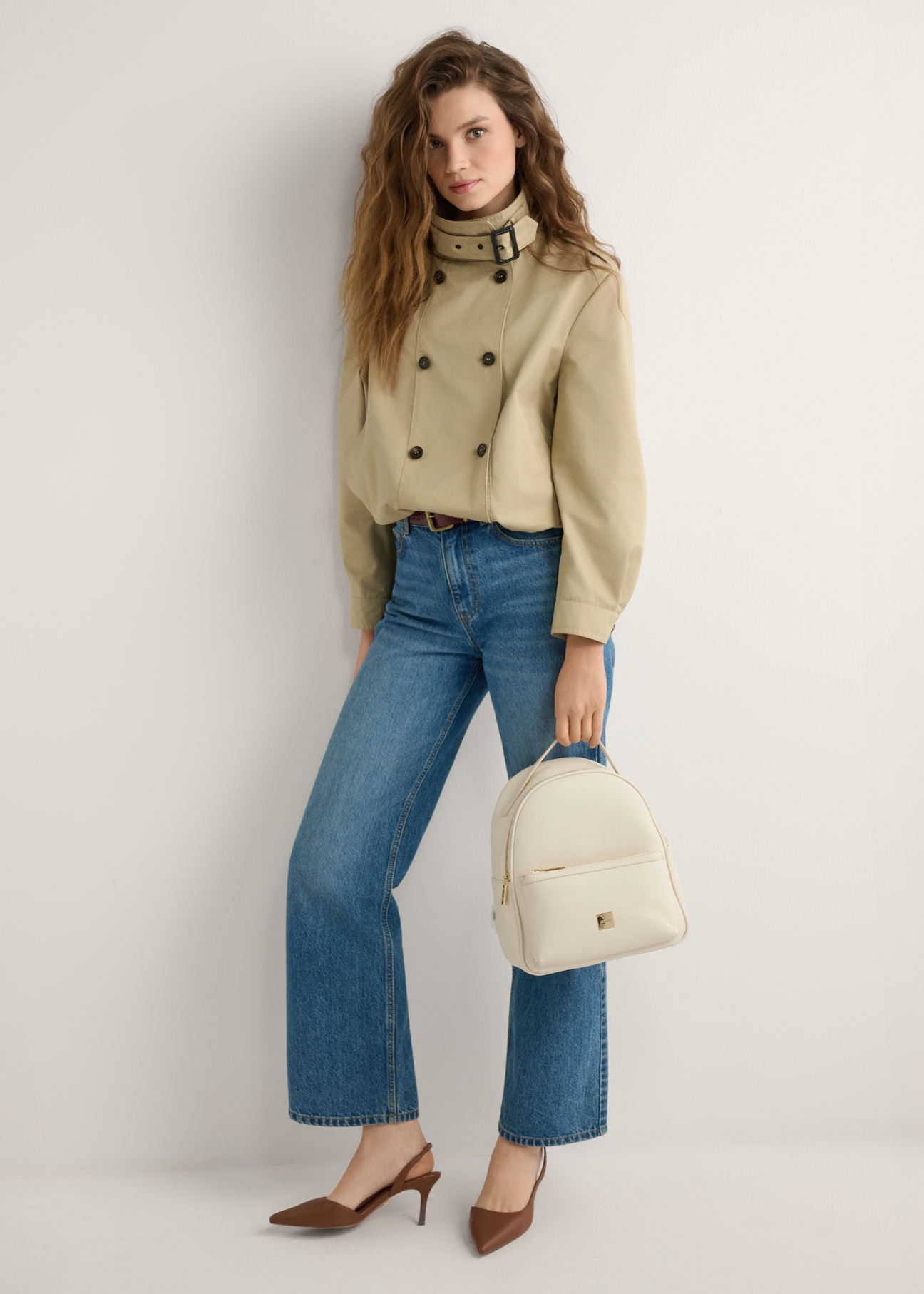 Kremowy damski średni plecak TOREC-0920-0B(W26), widok produktu w dłoni modelki. Widoczna cała sylwetka.