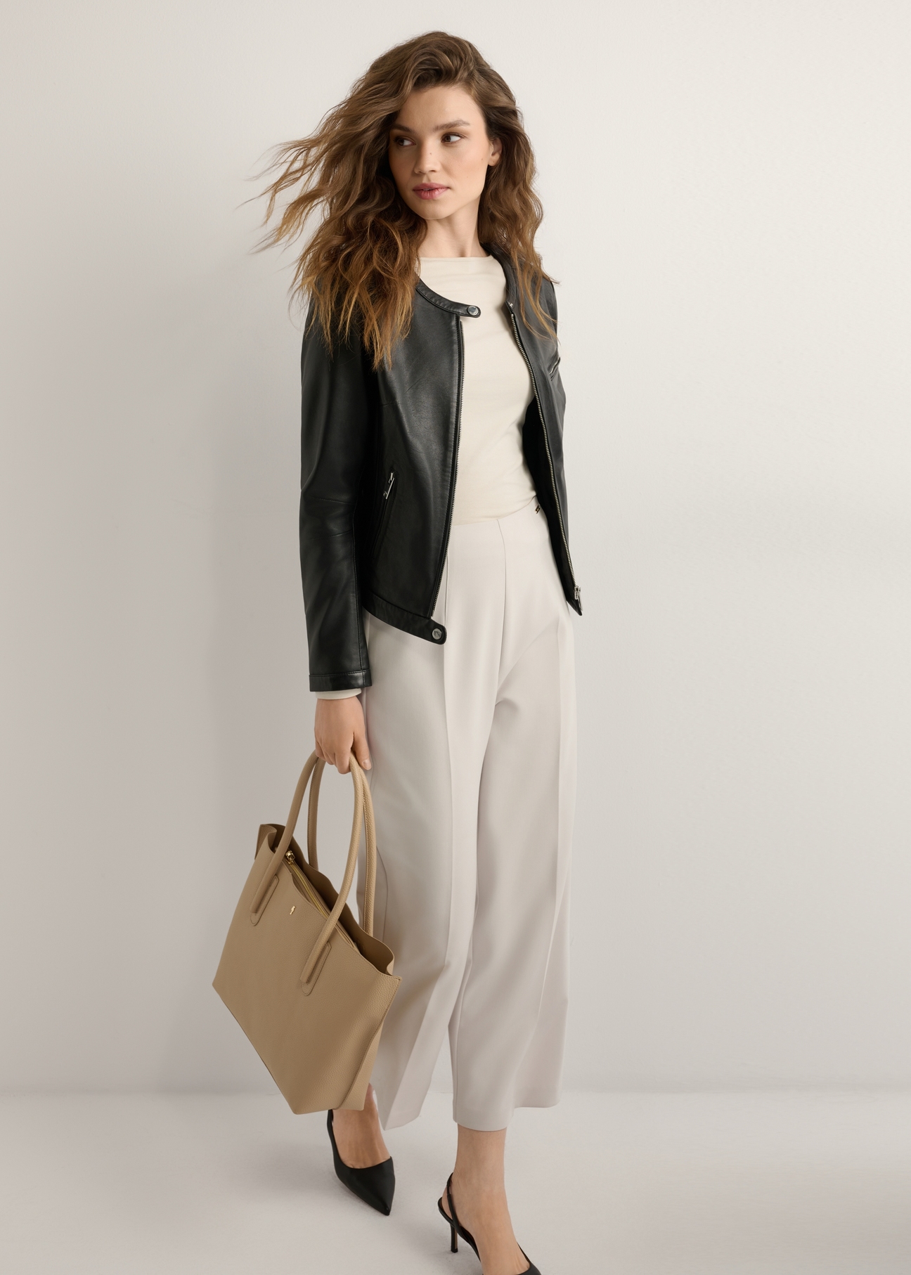 Ciemnobeżowa torebka shopper damska TOREC-0938-1C(W26), widok produktu skosem na modelce, widoczna cała sylwetka.